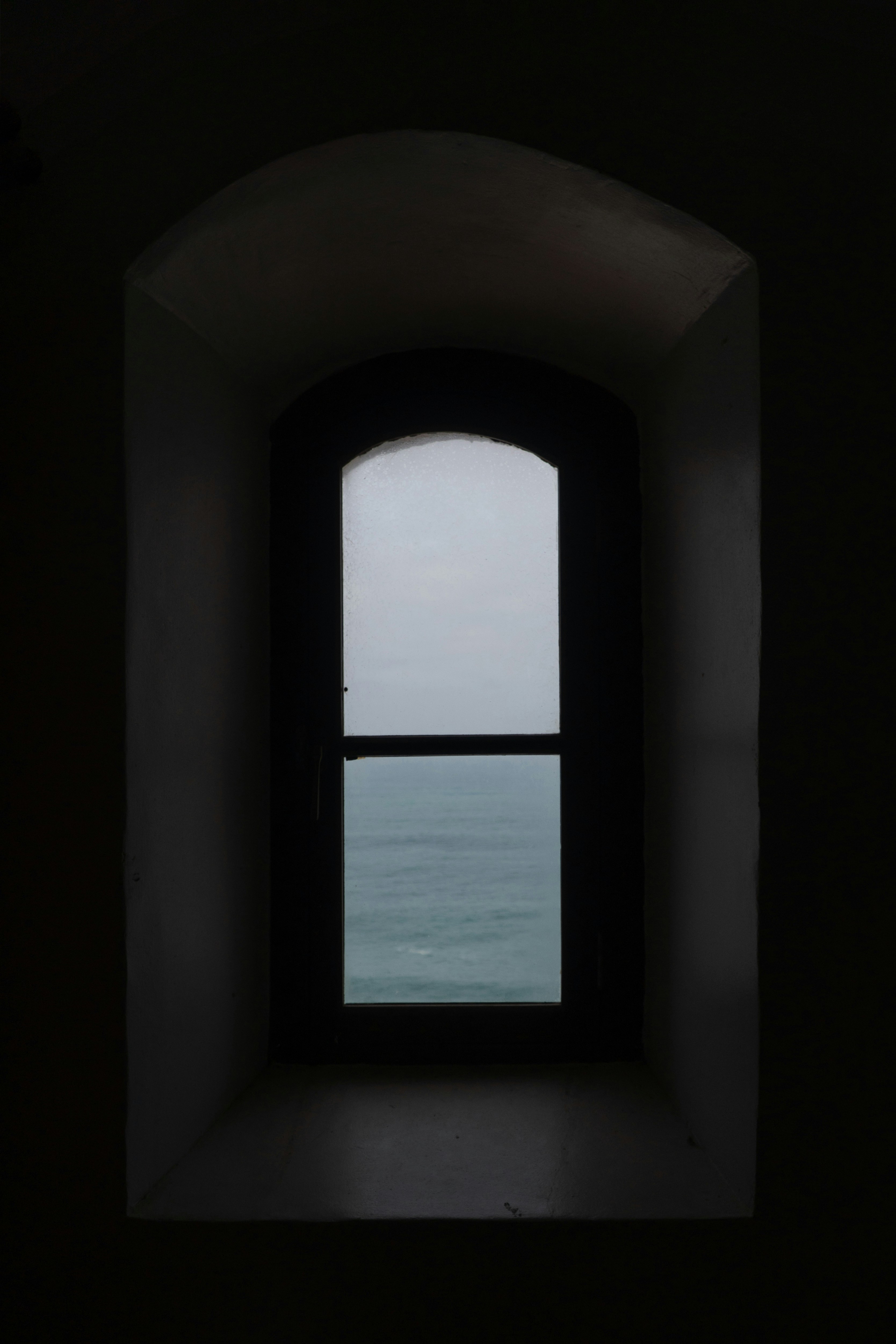 Dark window frame overlooking a calm ocean