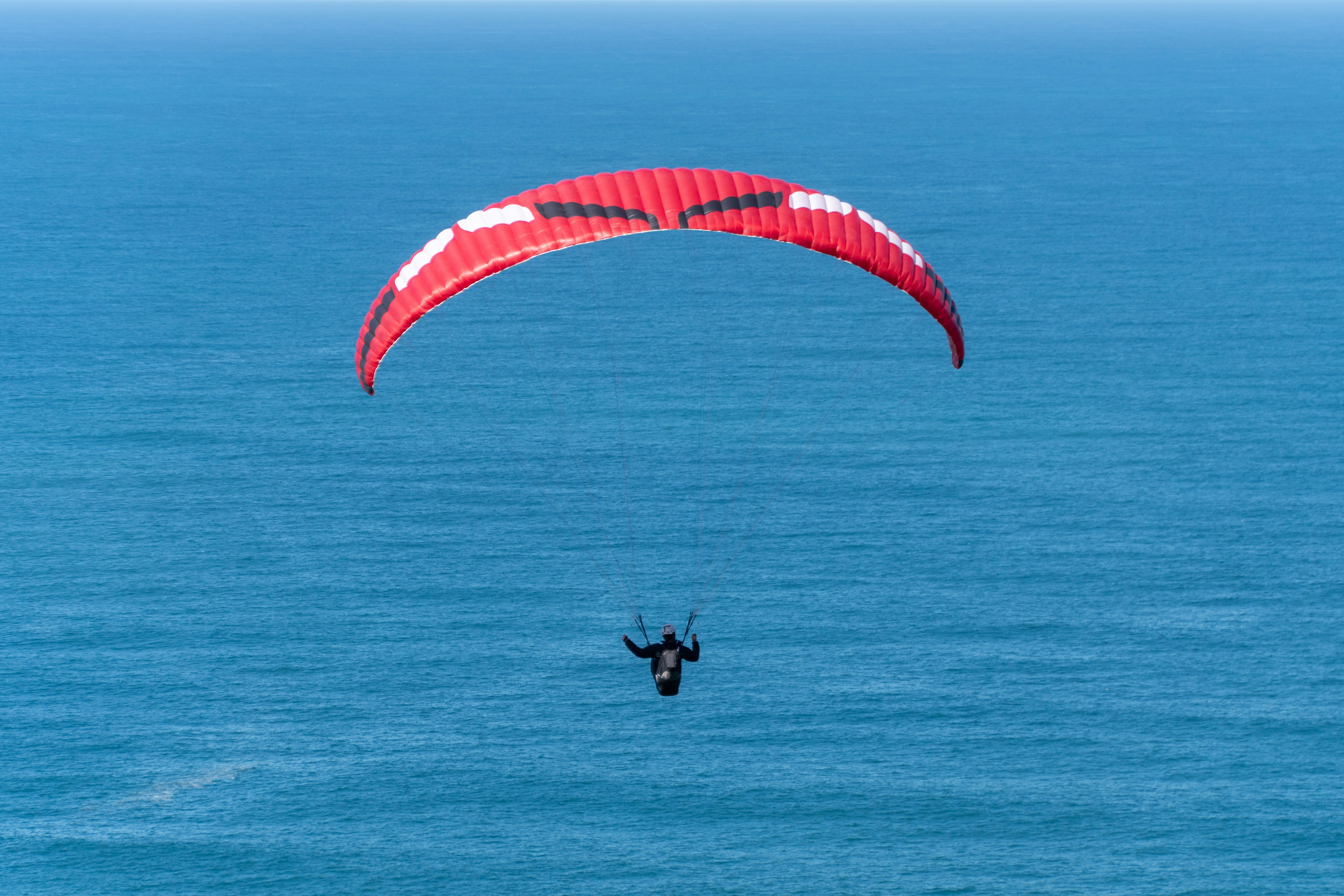 Paraglider soaring over a blue ocean