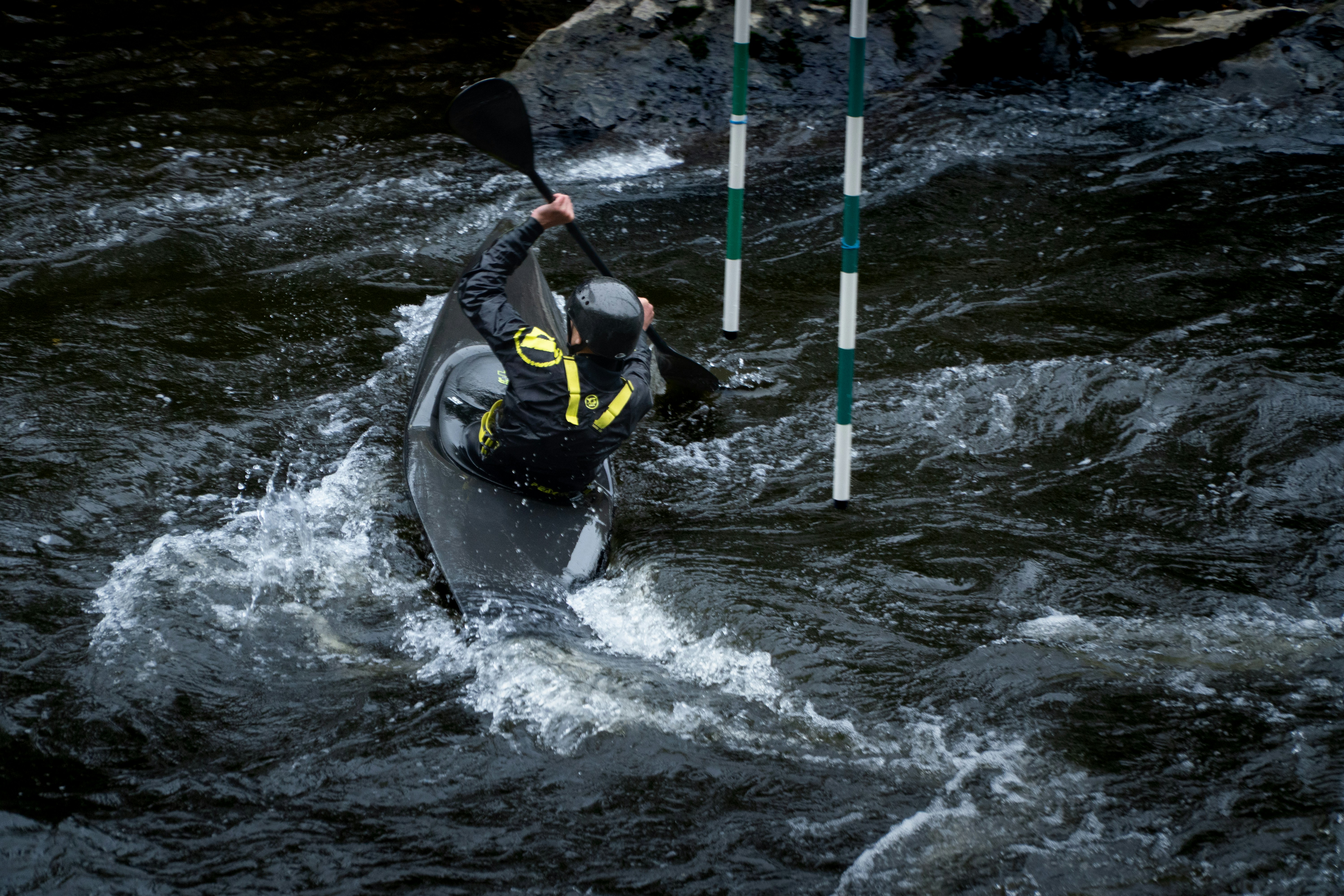 A kayaker navigates whitewater rapids near gates