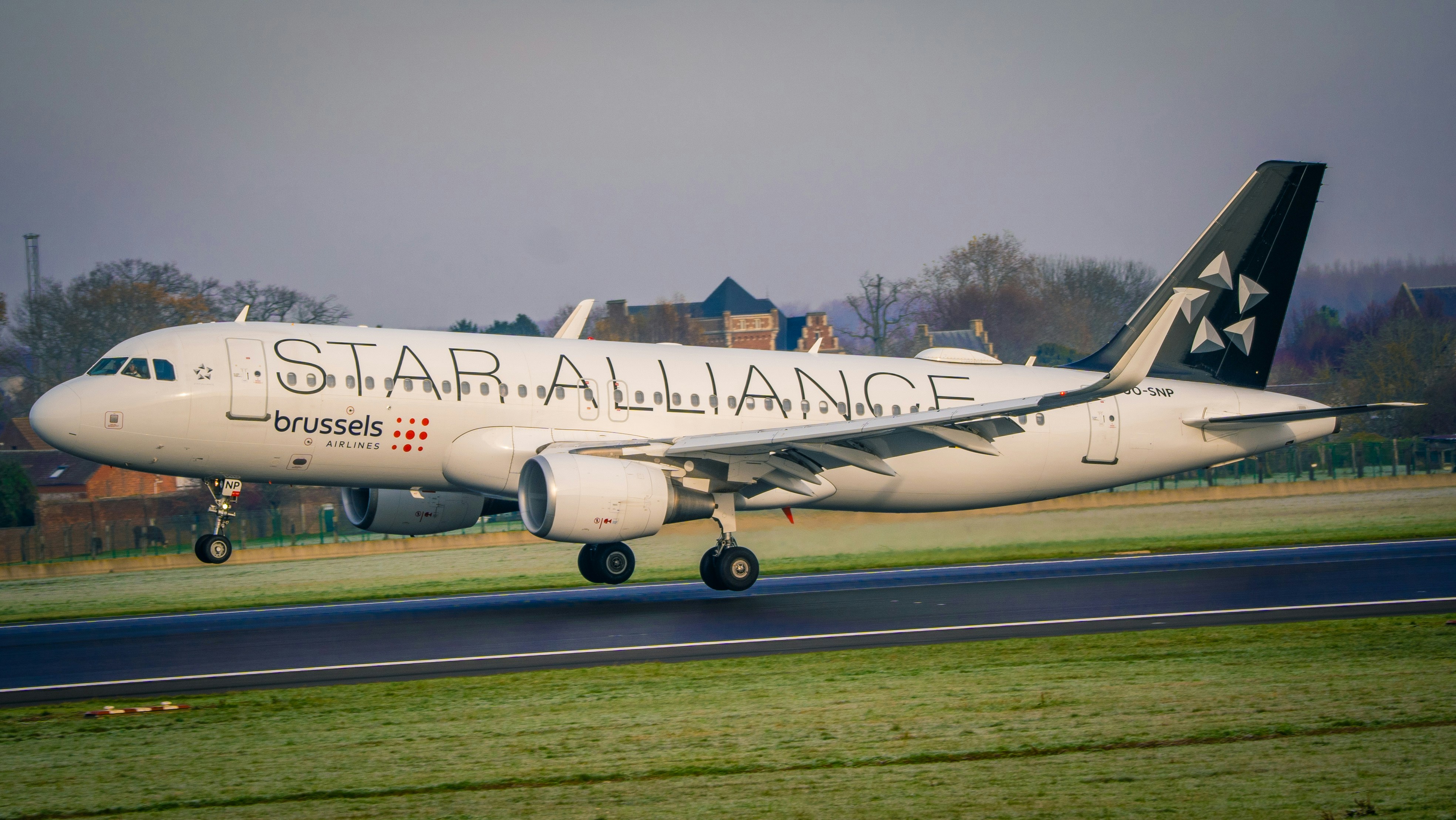Airplane with star alliance livery landing on runway.