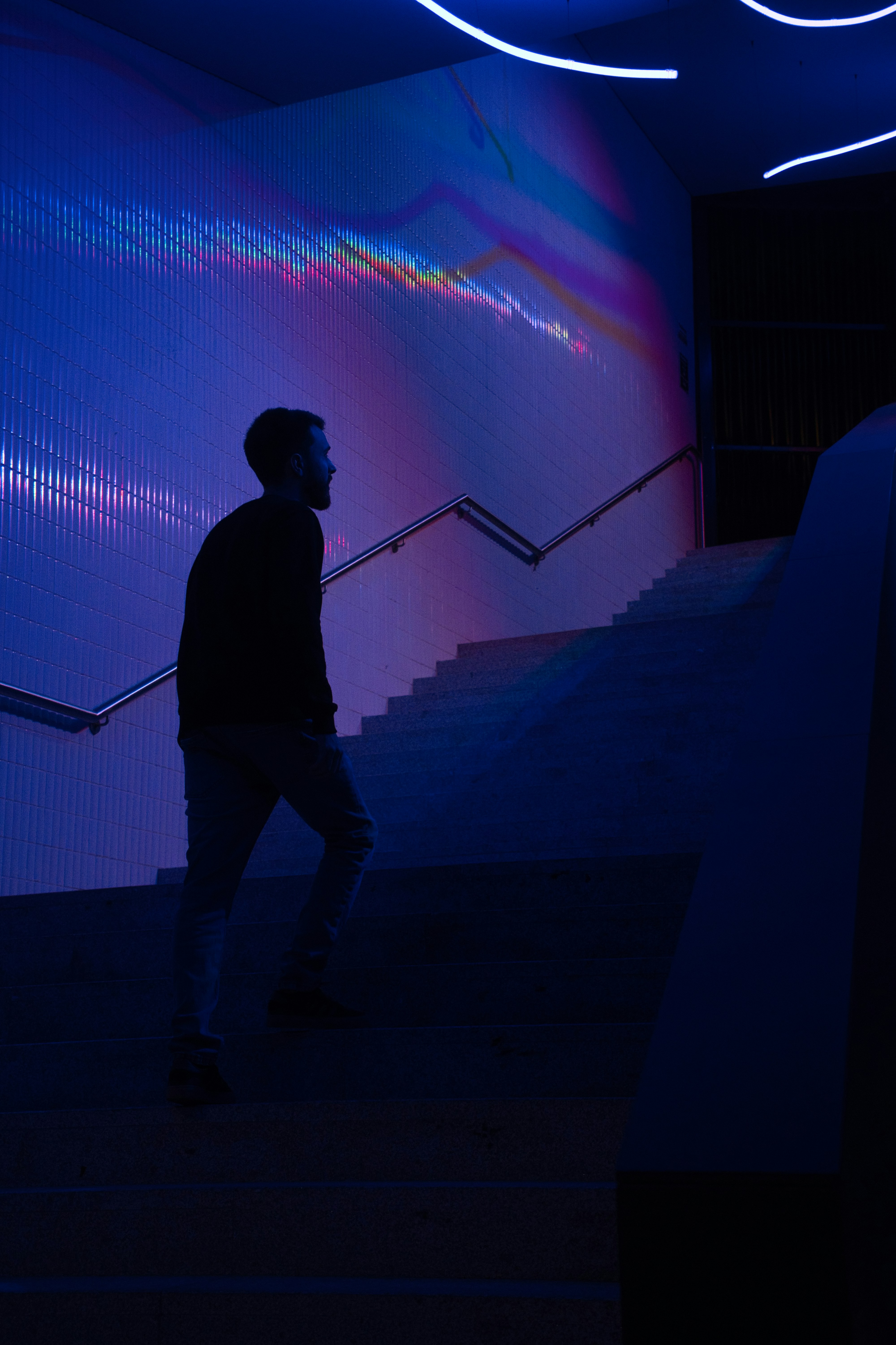 Man ascends illuminated stairs with colorful light patterns