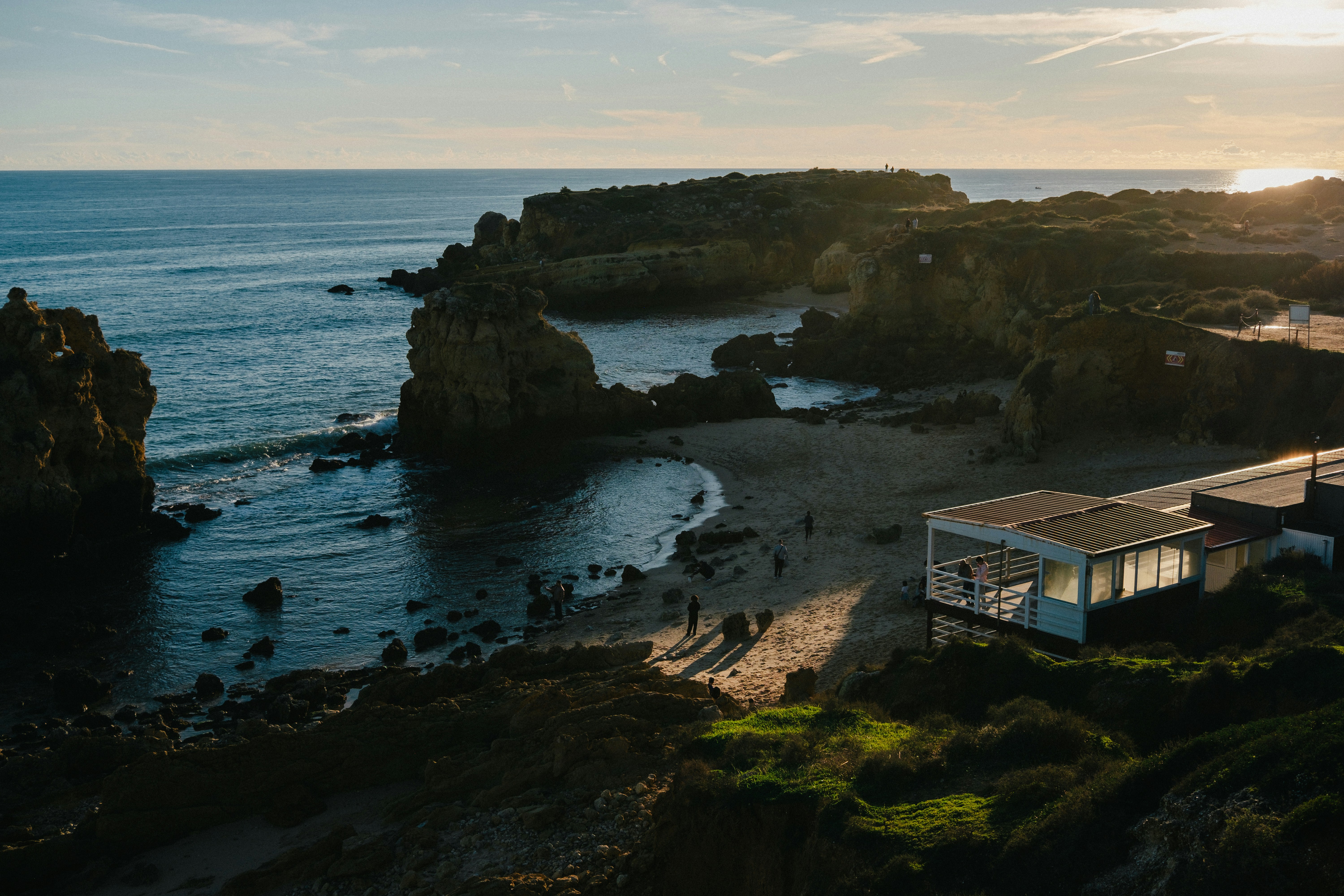 Coastal landscape with a modern building and people on beach.