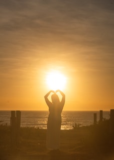 Silhouette of a person making a heart shape at sunset.
