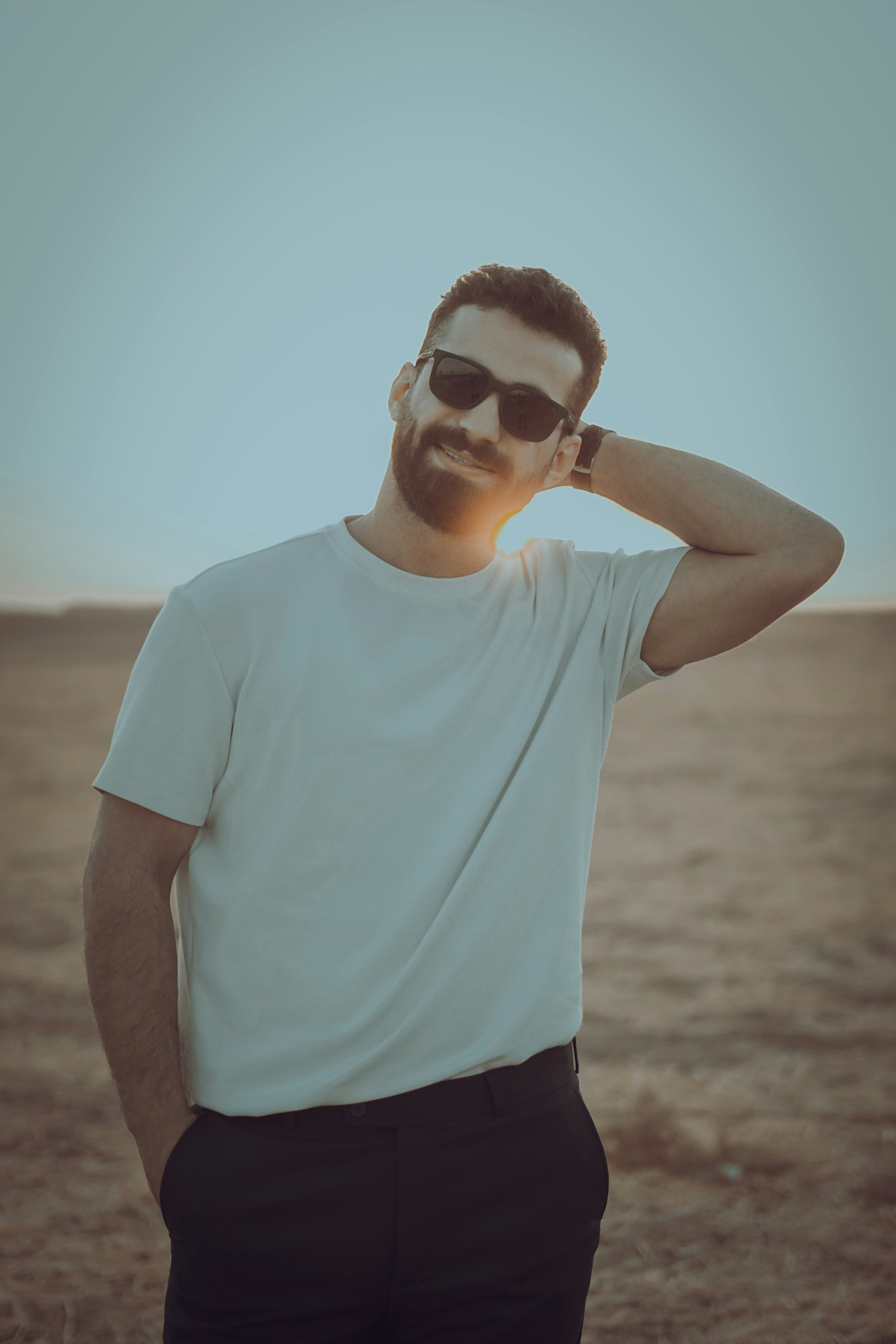 Man in sunglasses posing outdoors at sunset