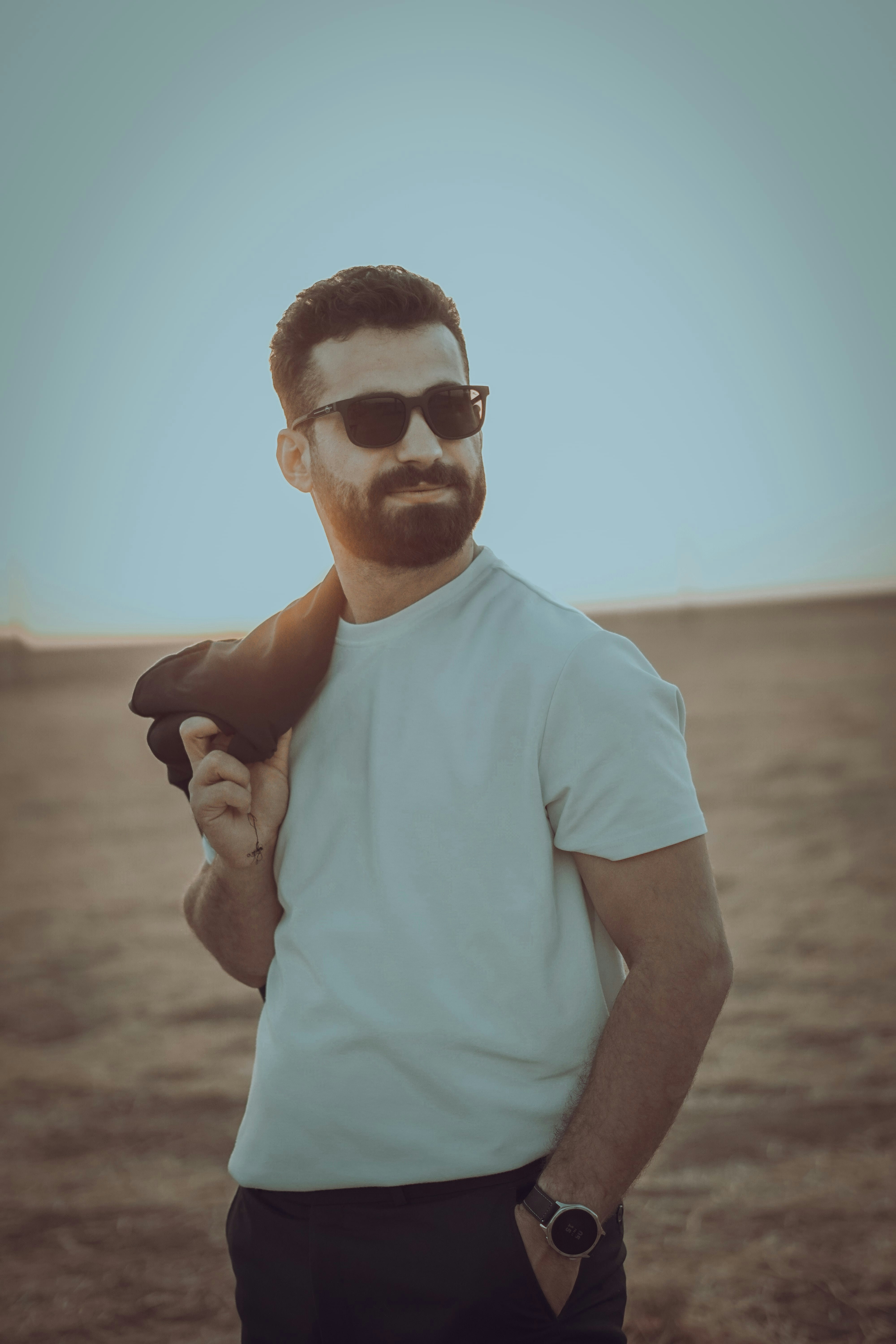 Man wearing sunglasses holding jacket over shoulder