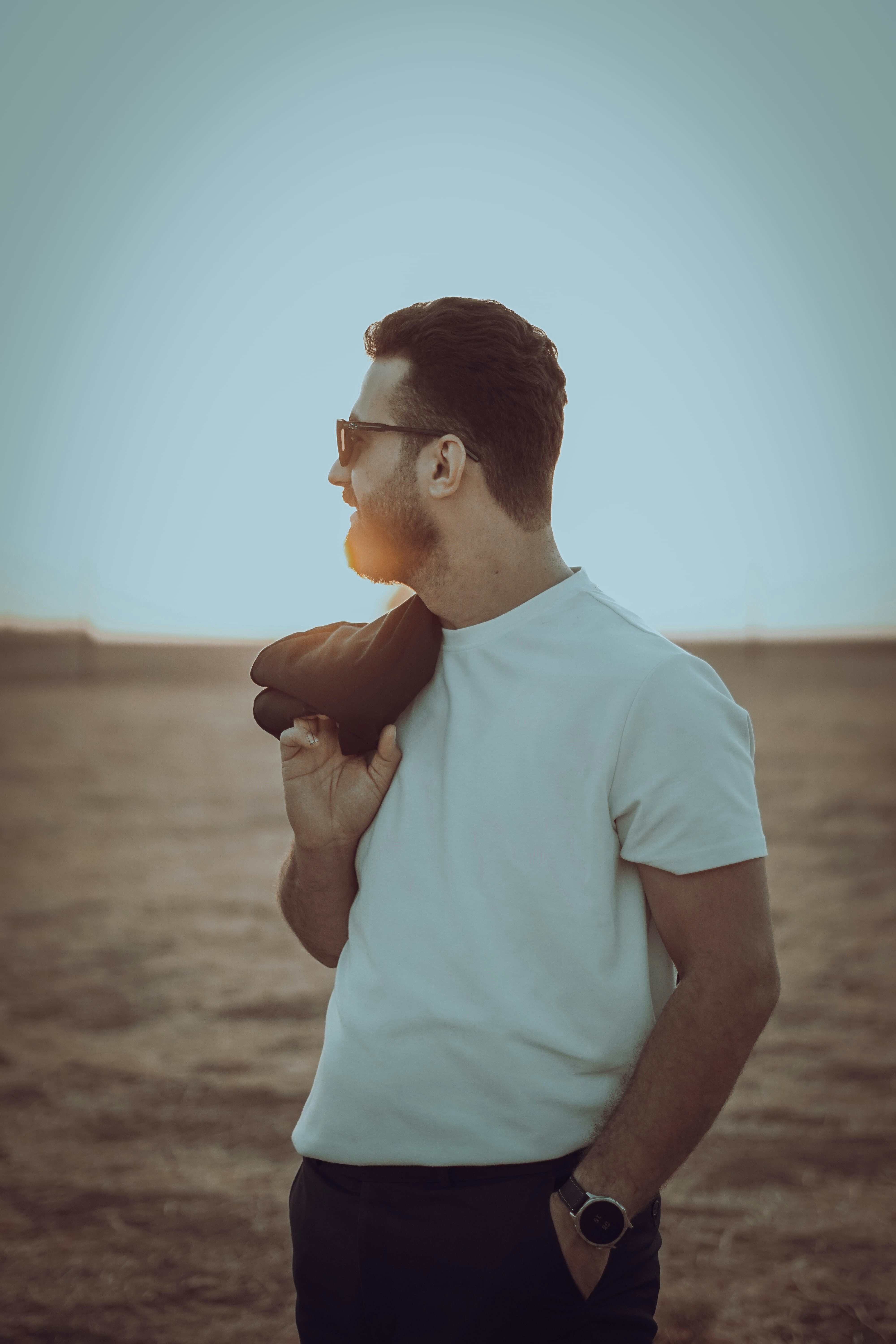 Man in sunglasses holding jacket over shoulder