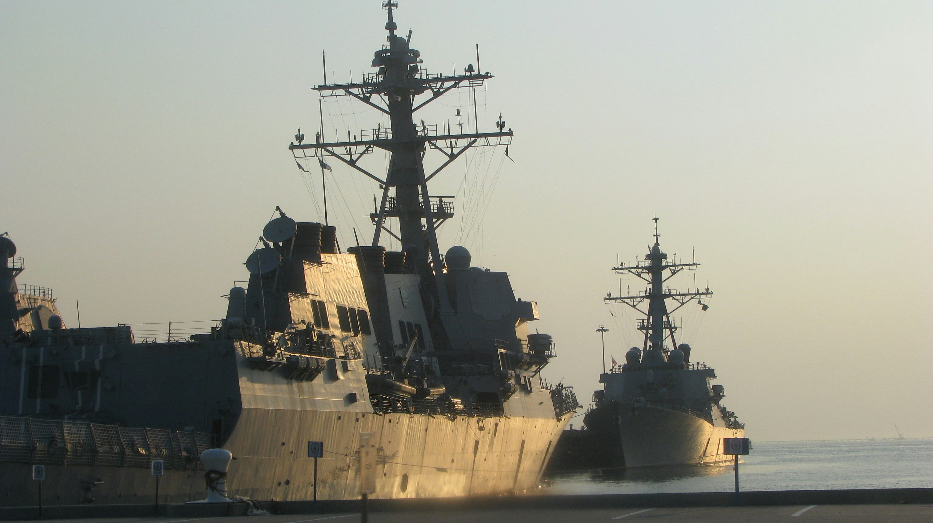 Several naval warships docked at a harbor.