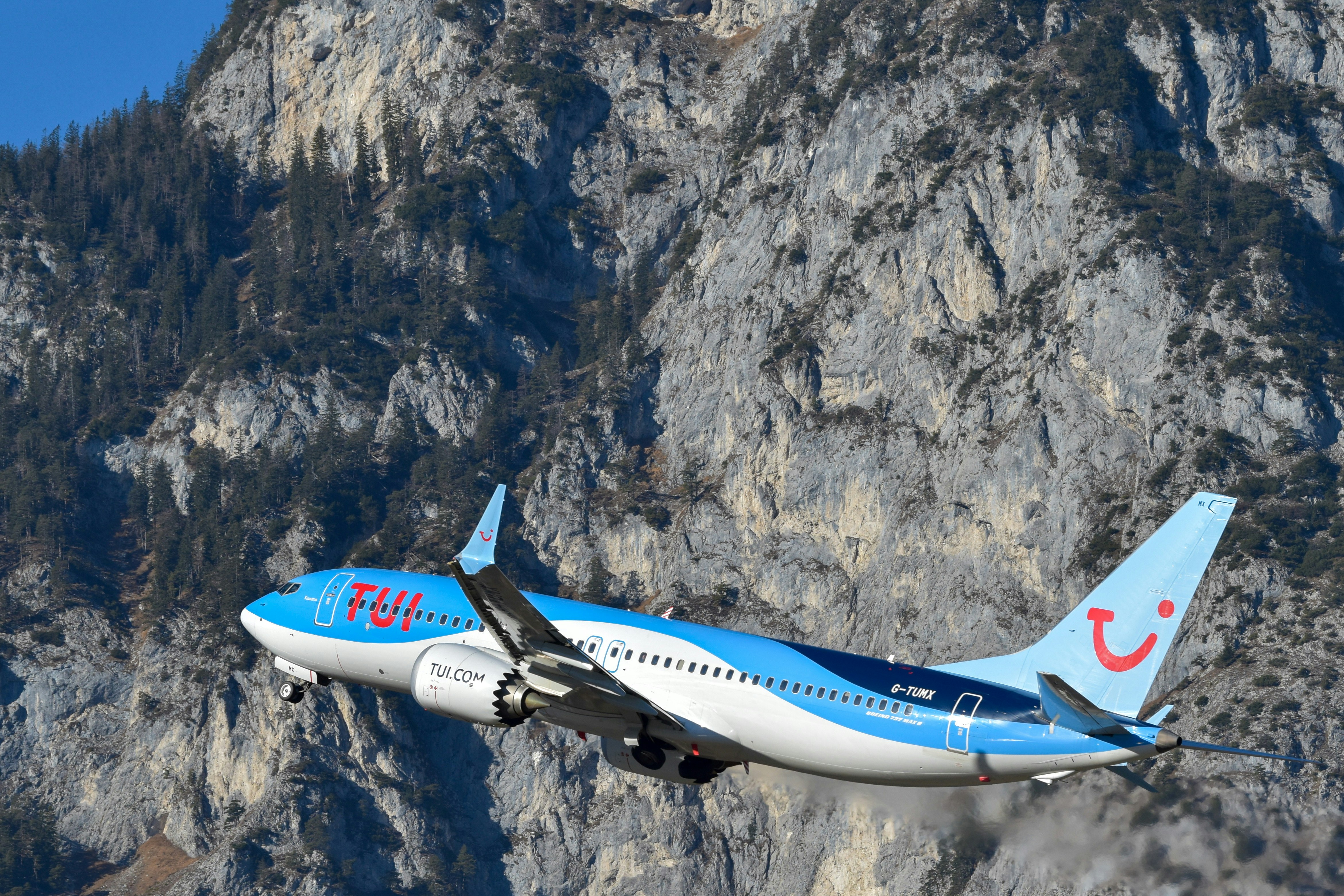 Avión Tui despegando con montañas de fondo