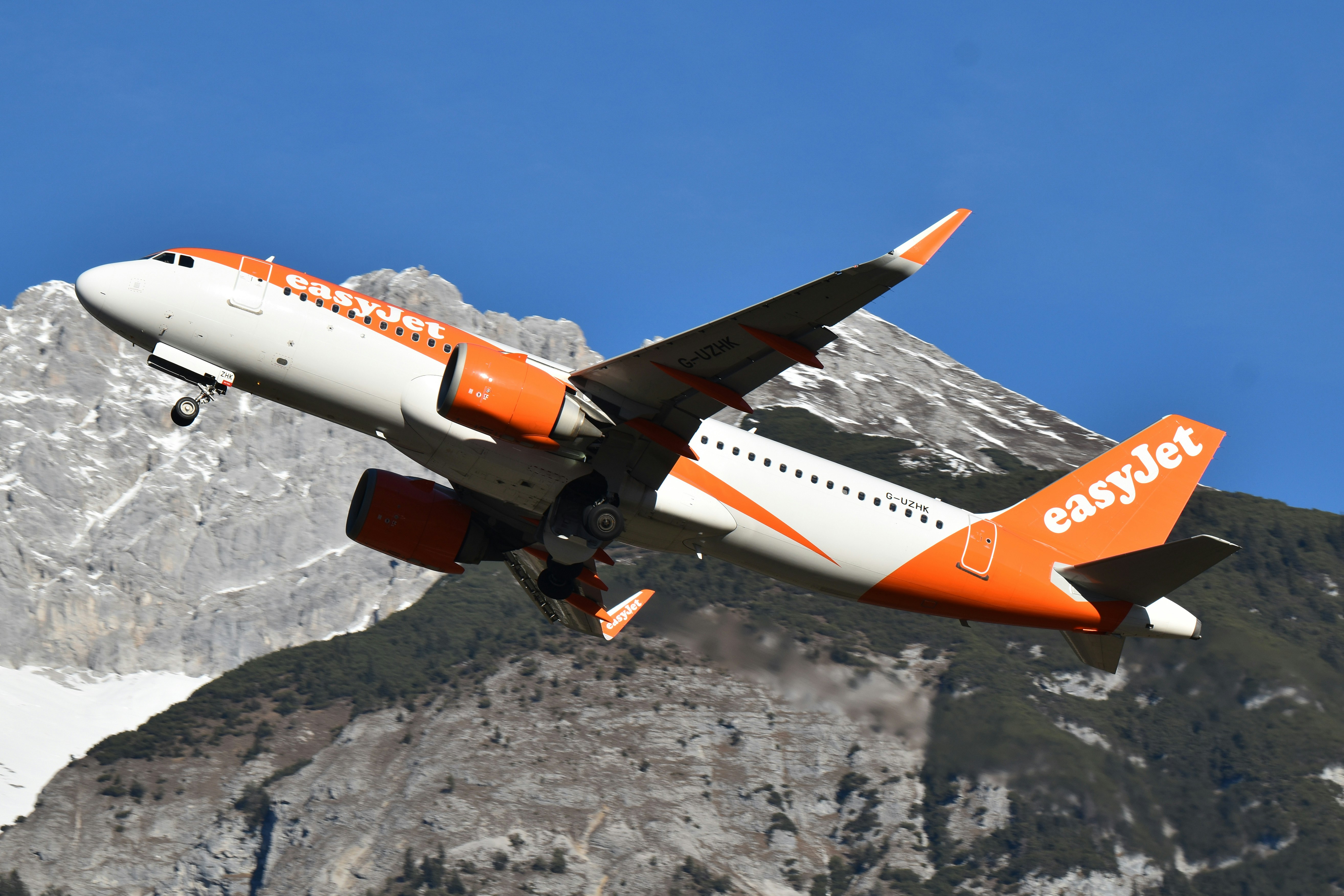 Un avión easyjet volando junto a una montaña nevada.
