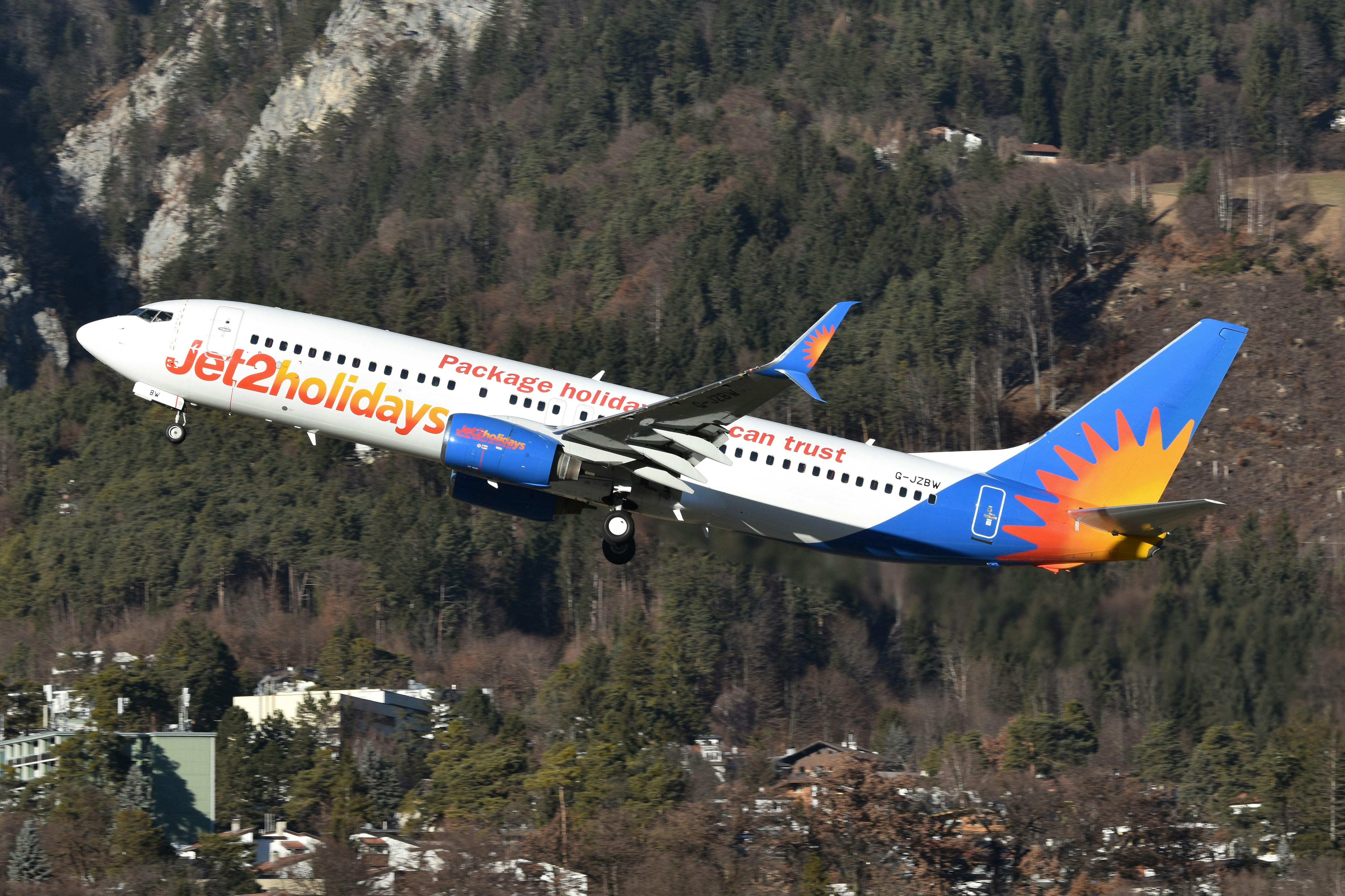 Un avión jet2holidays despega cerca de montañas.