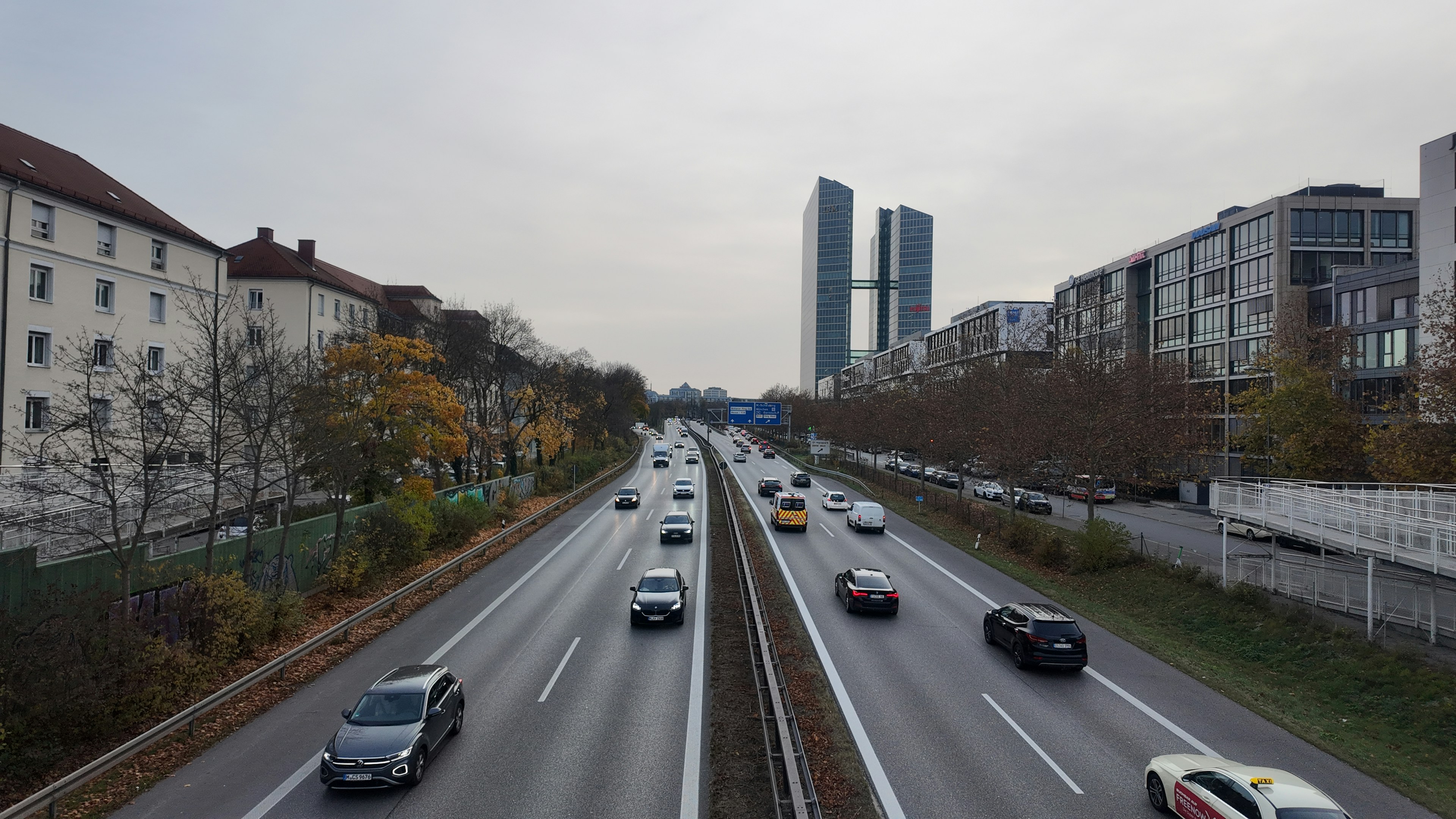 Autos, die auf einer Autobahn mit Gebäuden im Hintergrund fahren, fahren