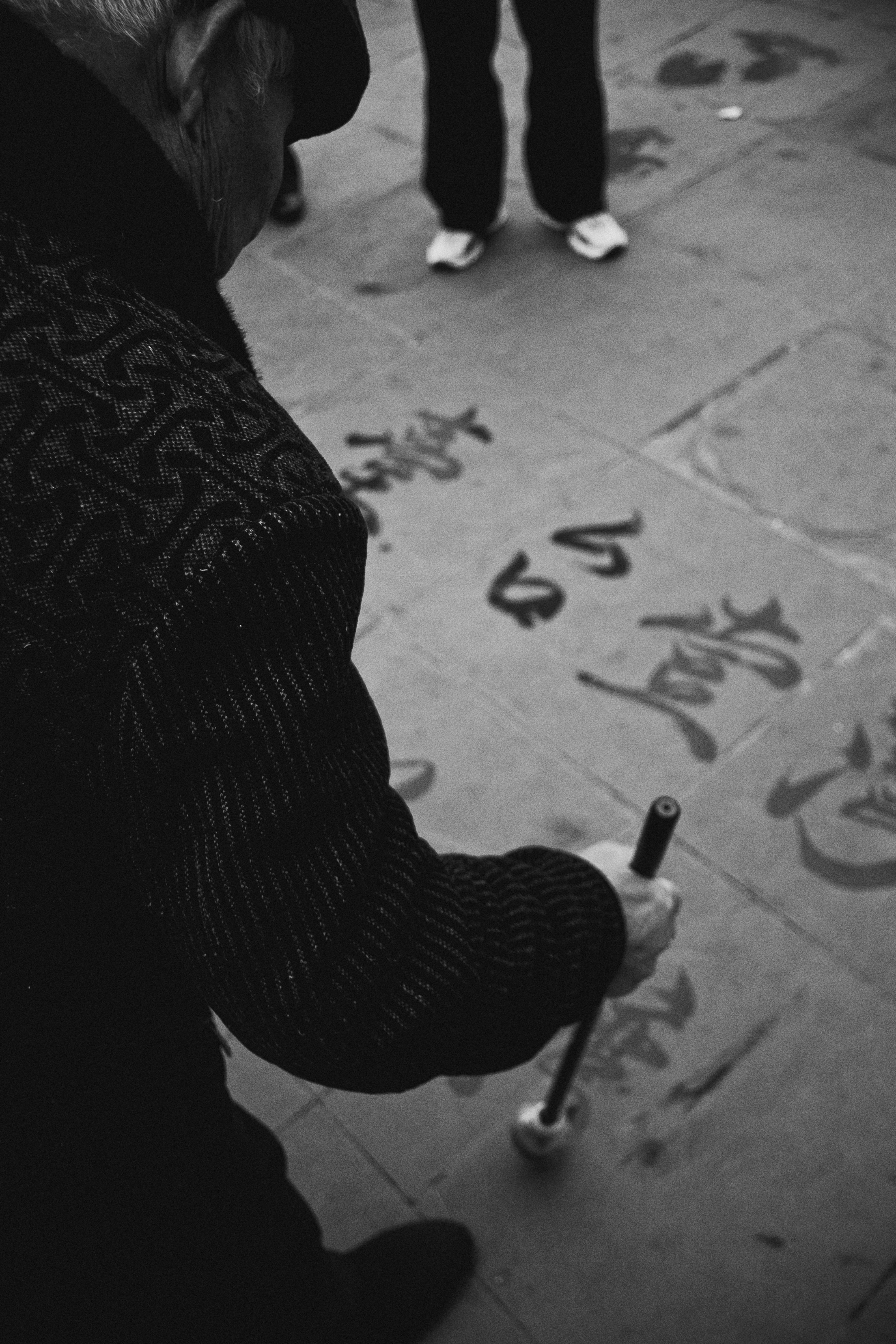 Persona mayor practicando caligrafía en el pavimento