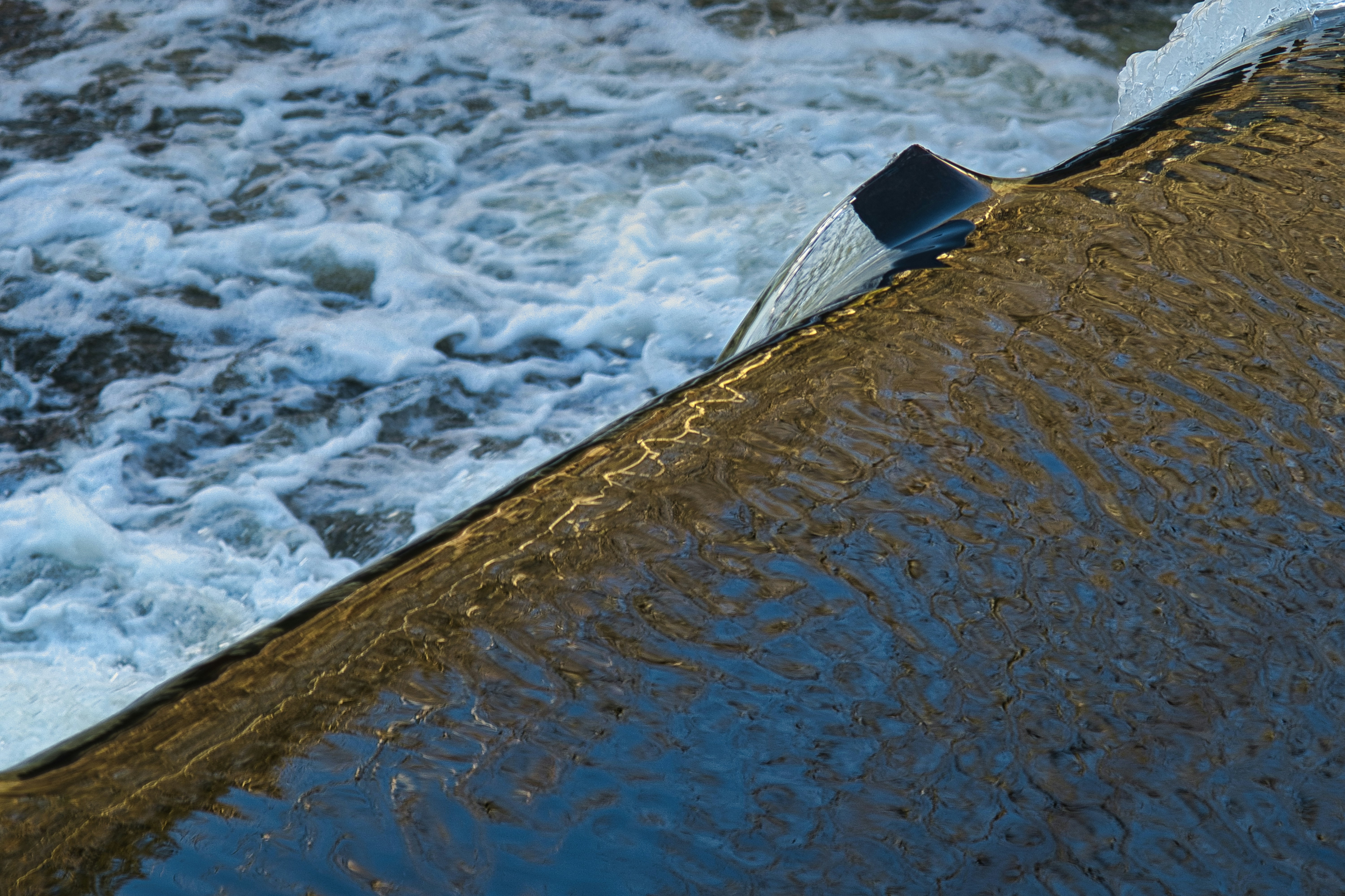 Water flowing over a dam spillway with foam.