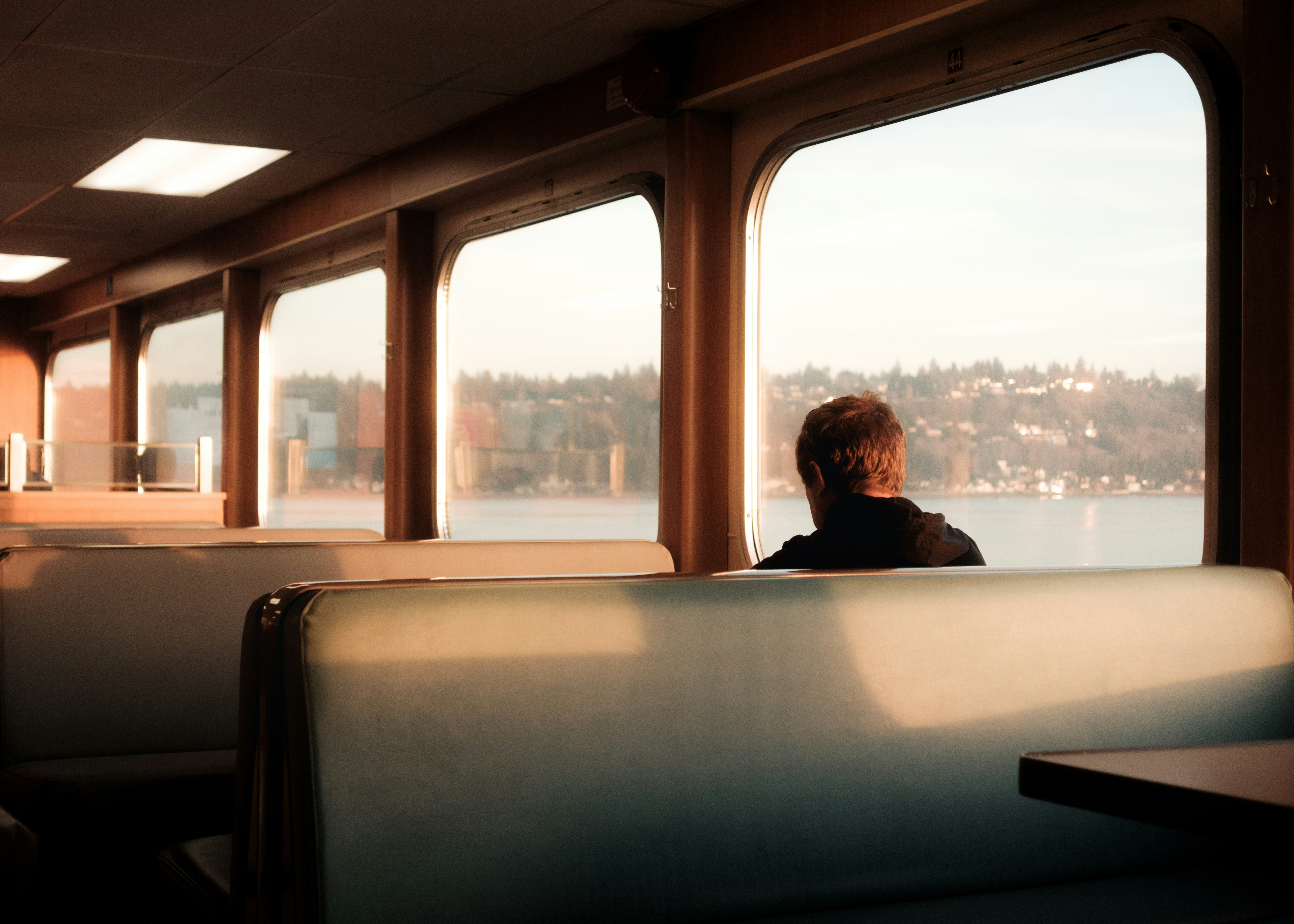 Man looking out ferry window at coastal town