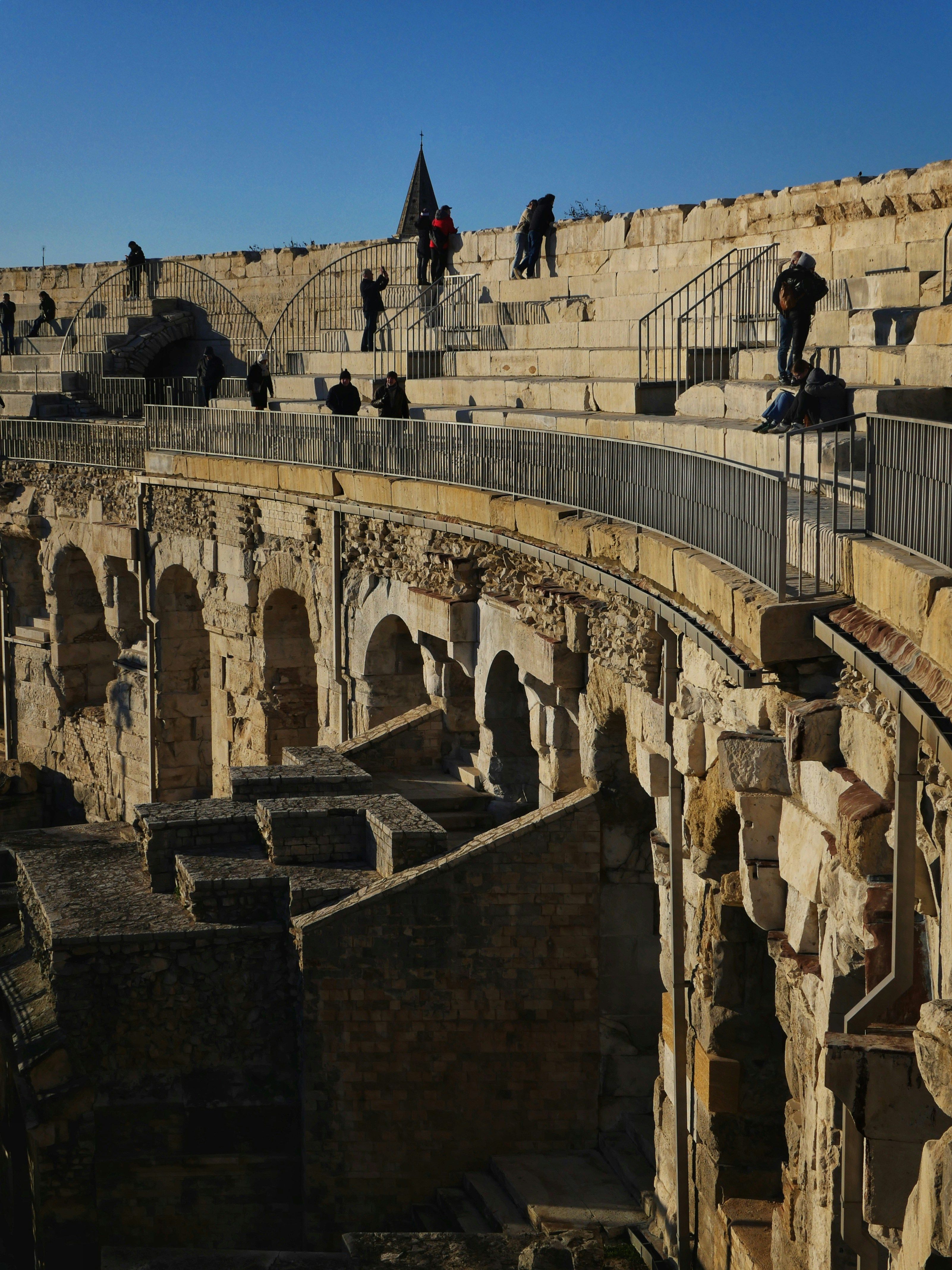 Ancient stone amphitheater with people on upper levels.
