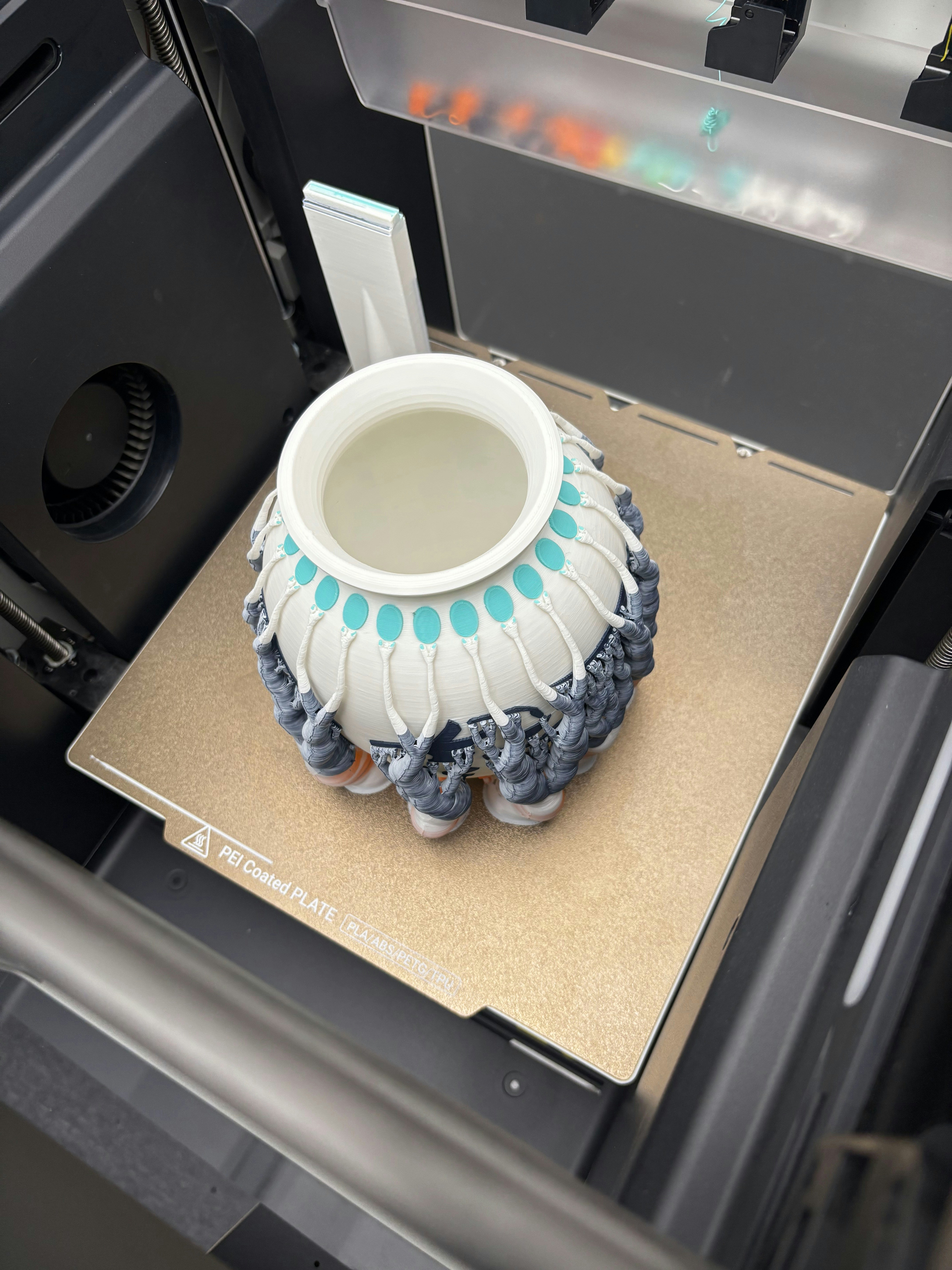 3D printer creating a white and blue vase