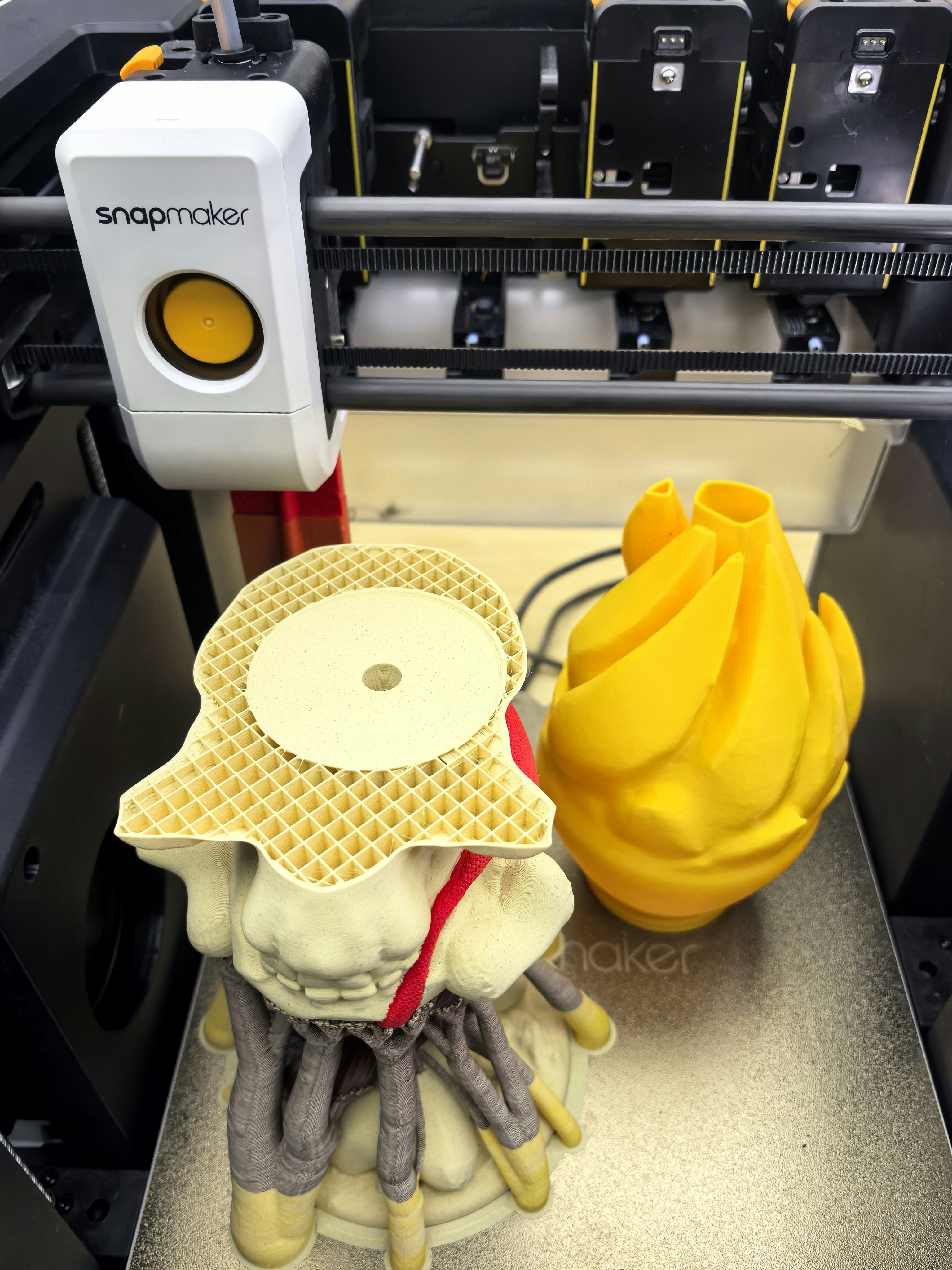 3D printer creating complex yellow and white objects.