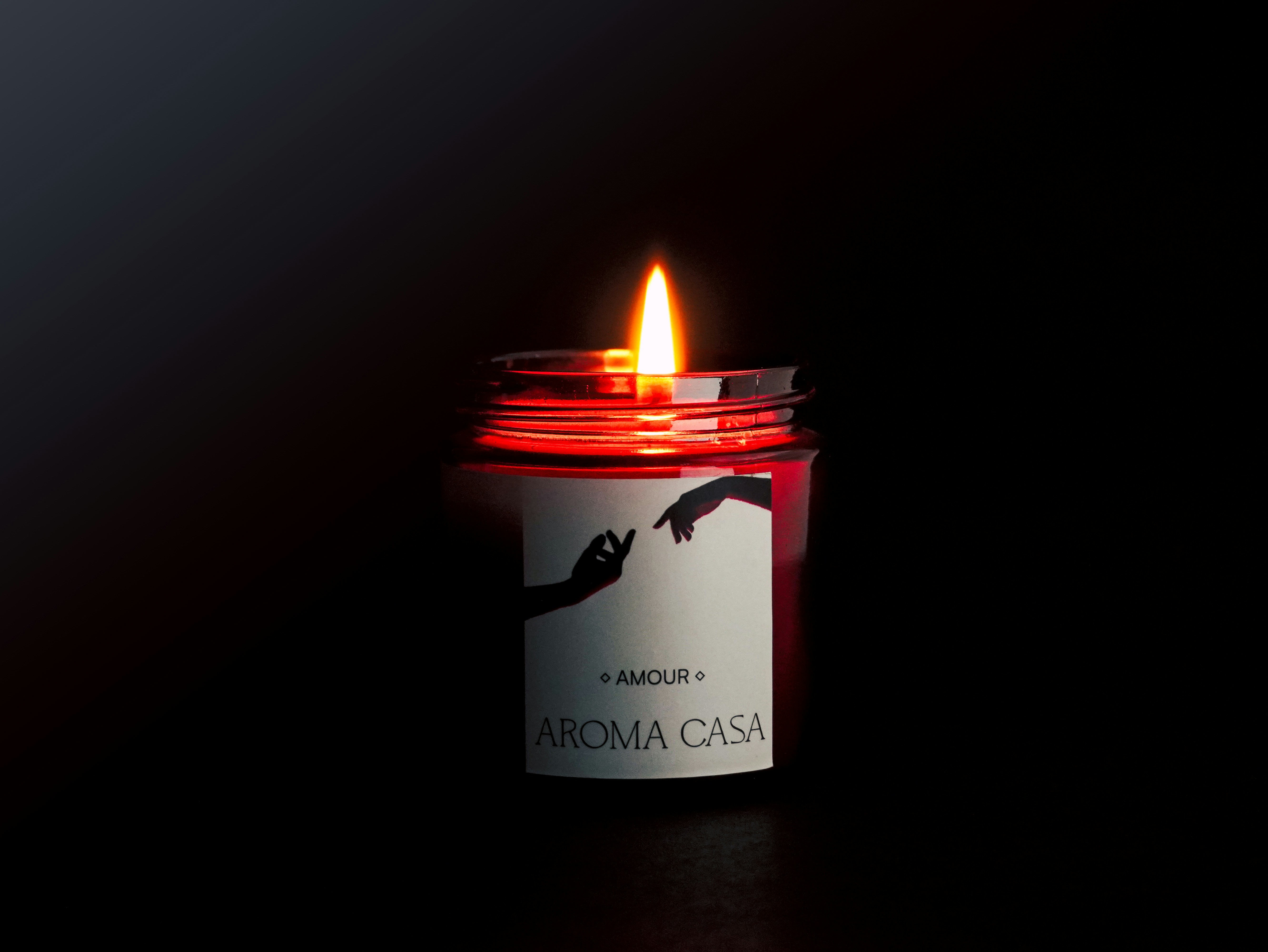 Lit red candle with label on dark background