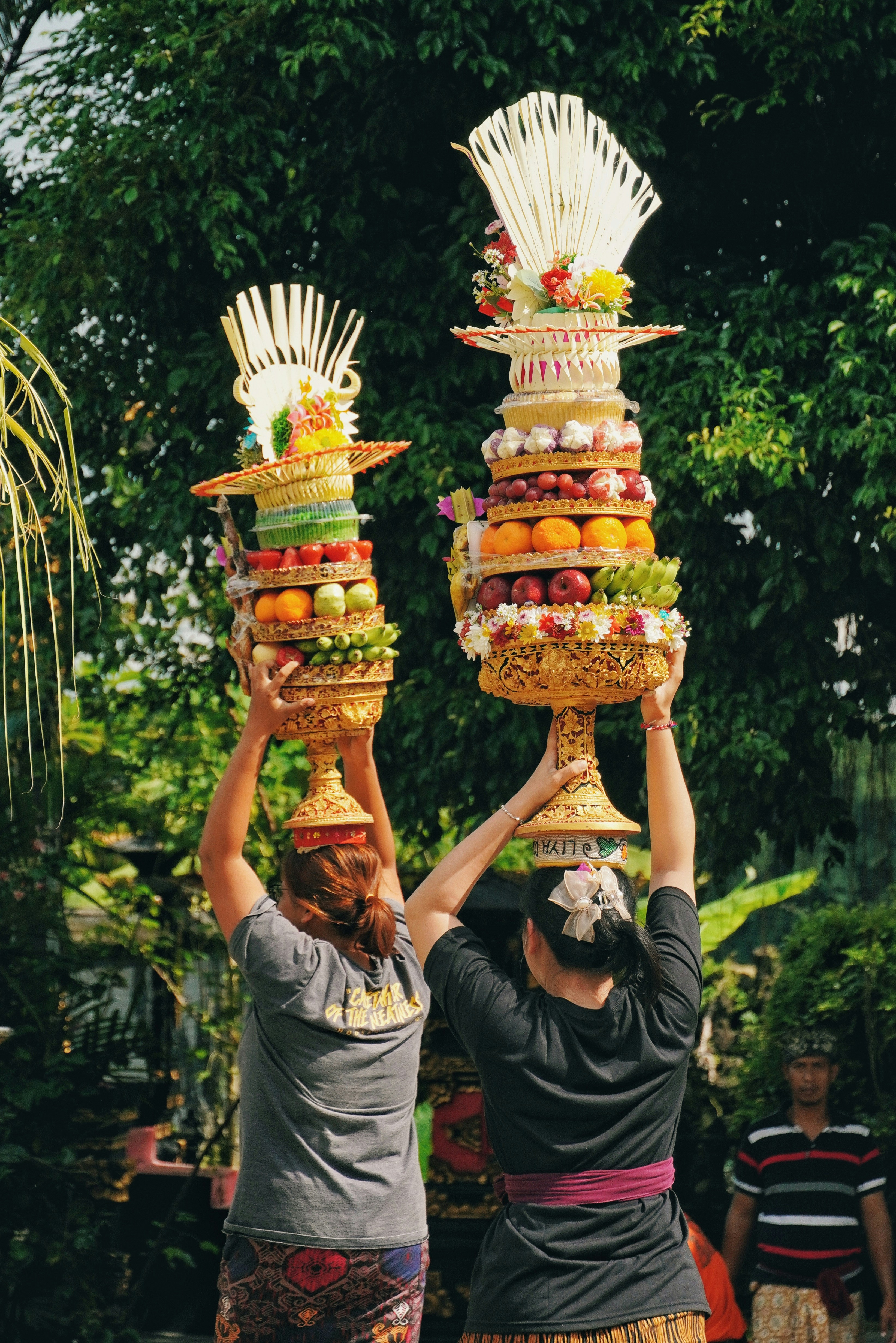 Dos personas llevando ofrendas elaboradas durante una ceremonia.