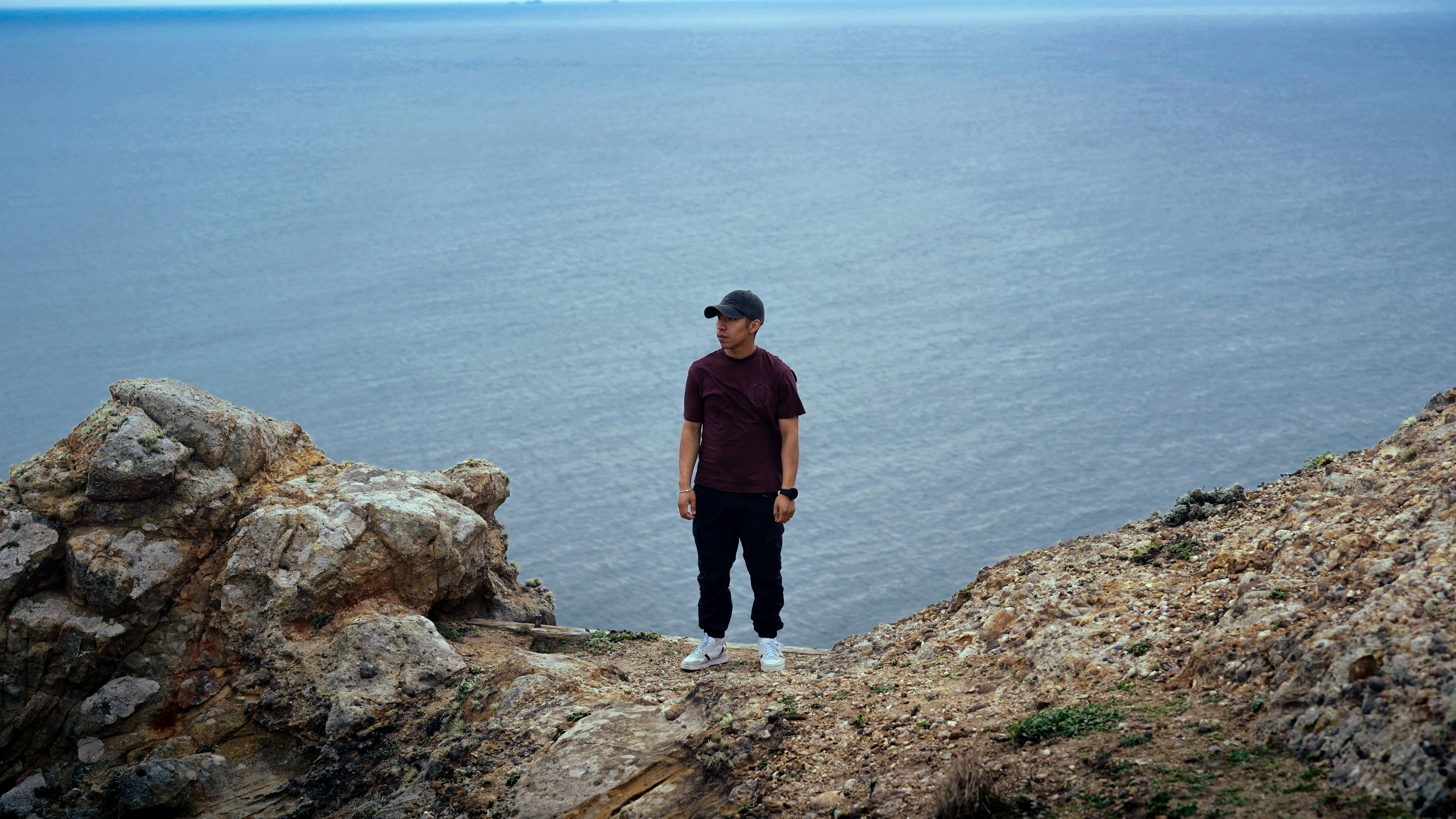 Mann steht auf einer Klippe mit Blick auf den Ozean