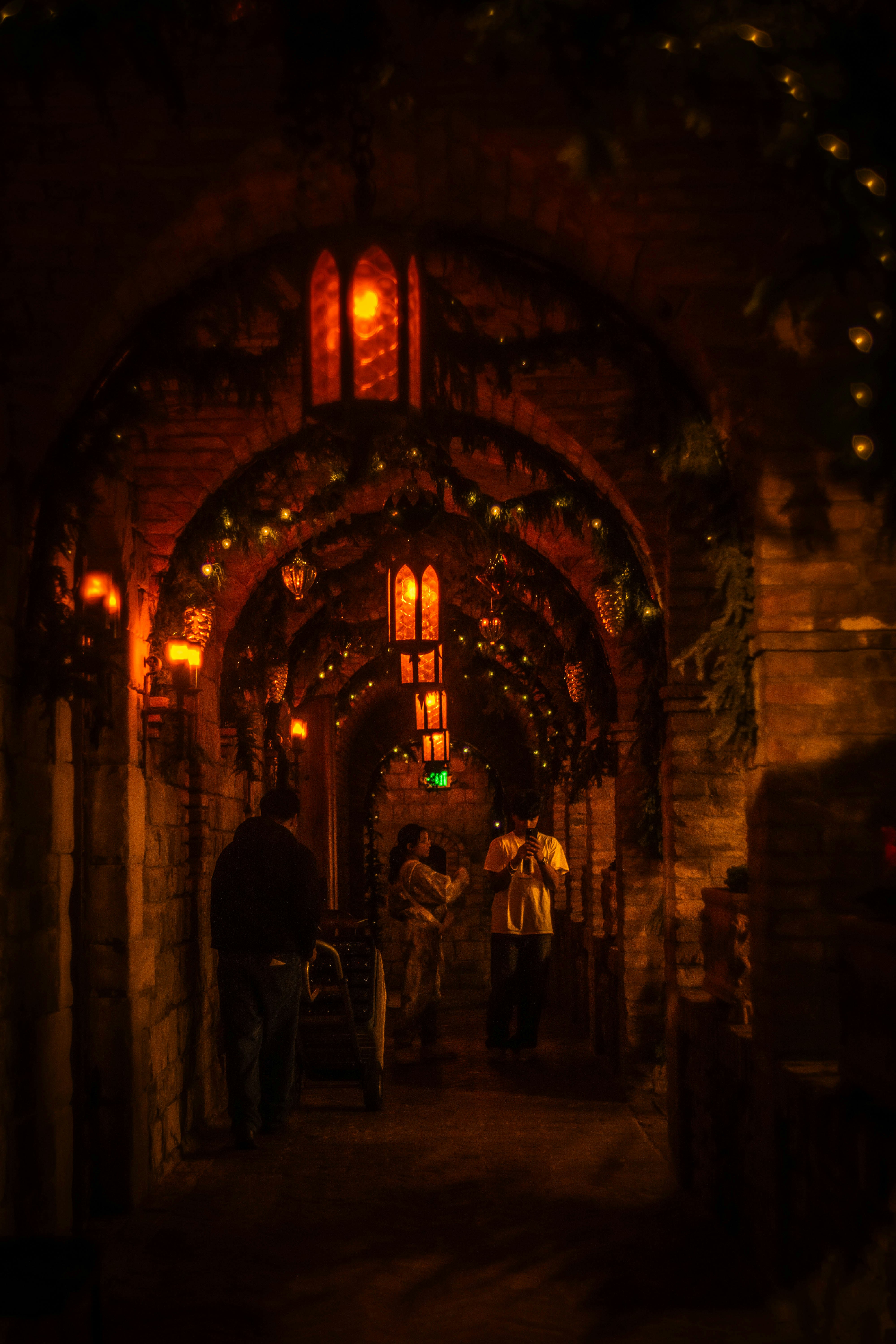 Le persone attraversano un corridoio ad arco poco illuminato con luci.