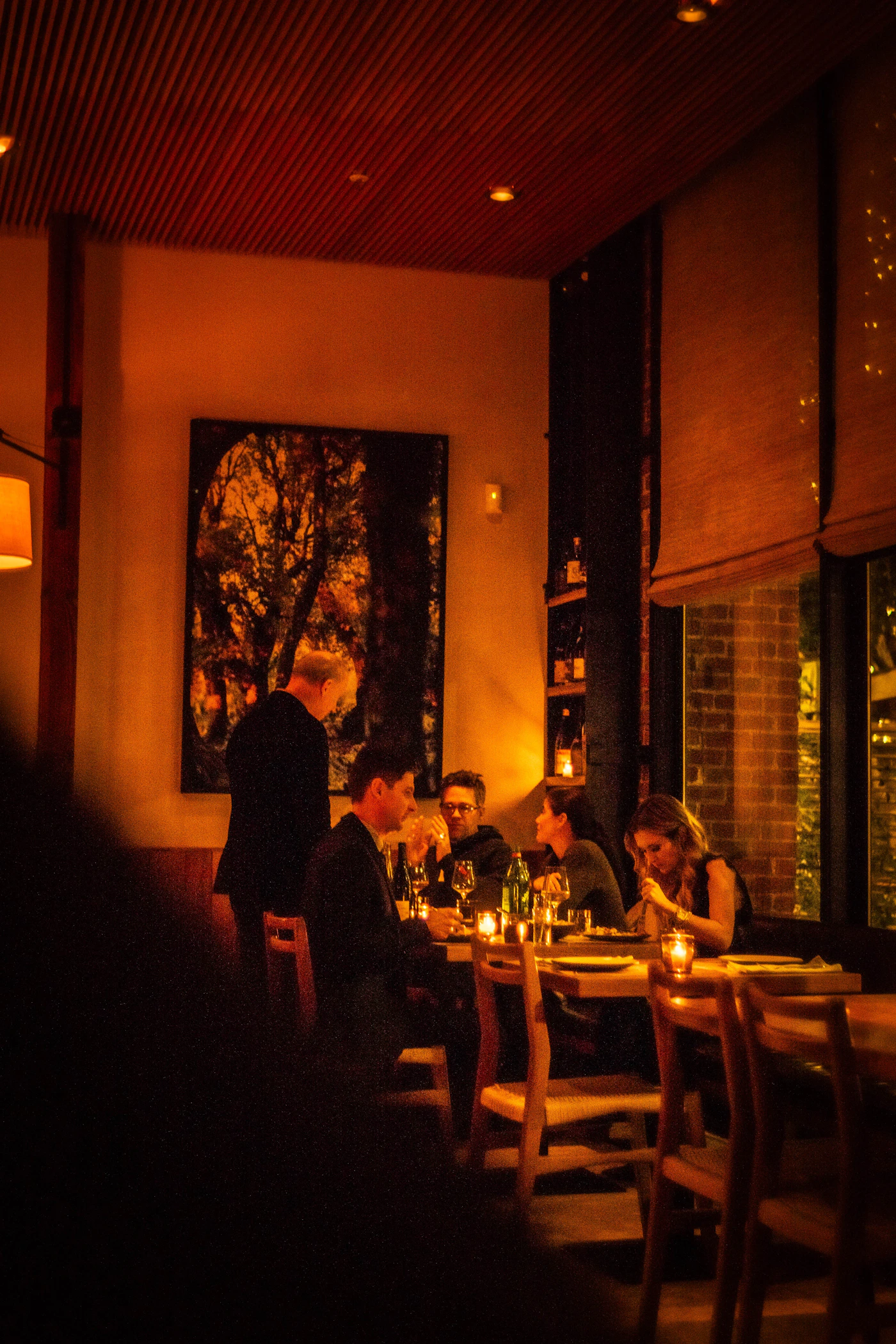 Elegant restaurant dining room with sophisticated atmosphere, guests at tables with warm ambient lighting
