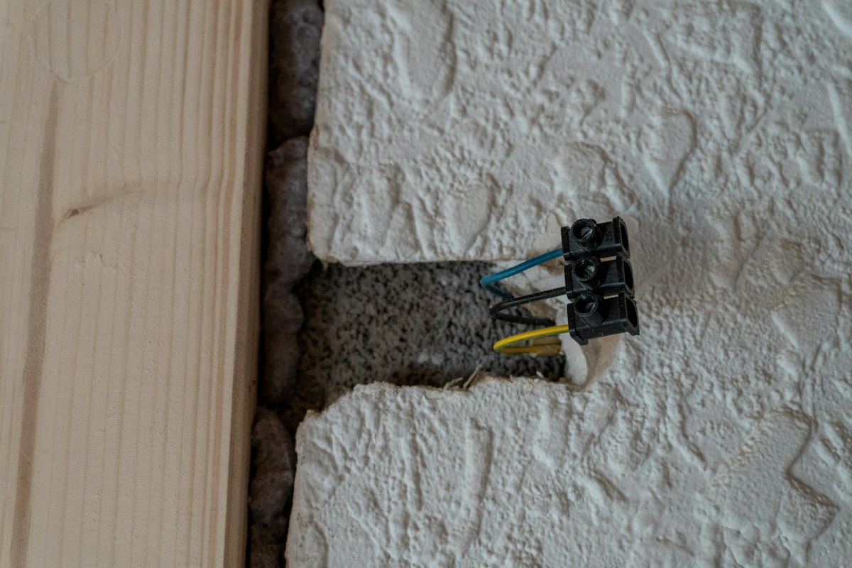 Cabos elétricos à vista numa abertura de parede durante a instalação elétrica de uma casa