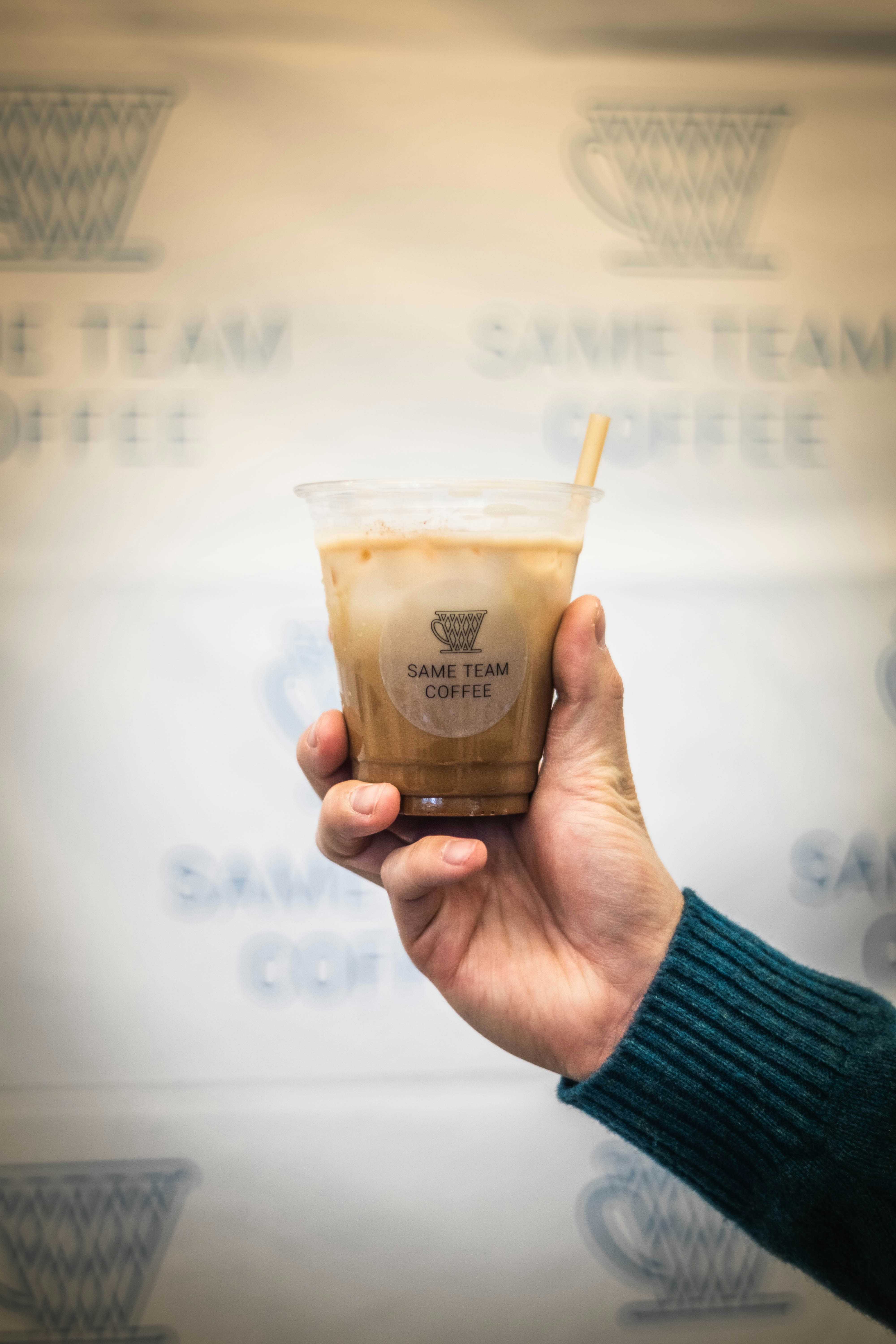 Hand holding a cold coffee drink with straw