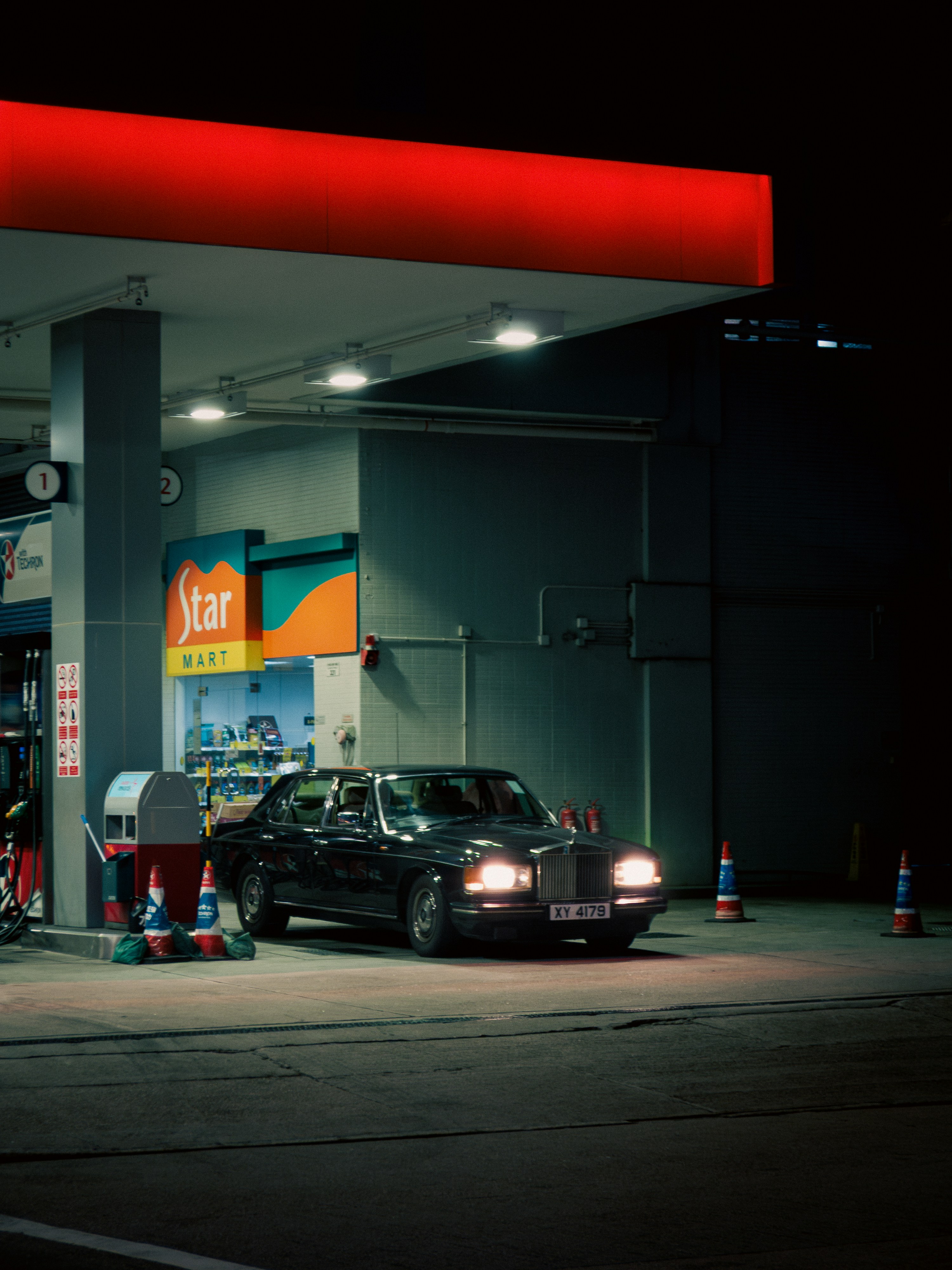 A black limousine parked at a gas station at night