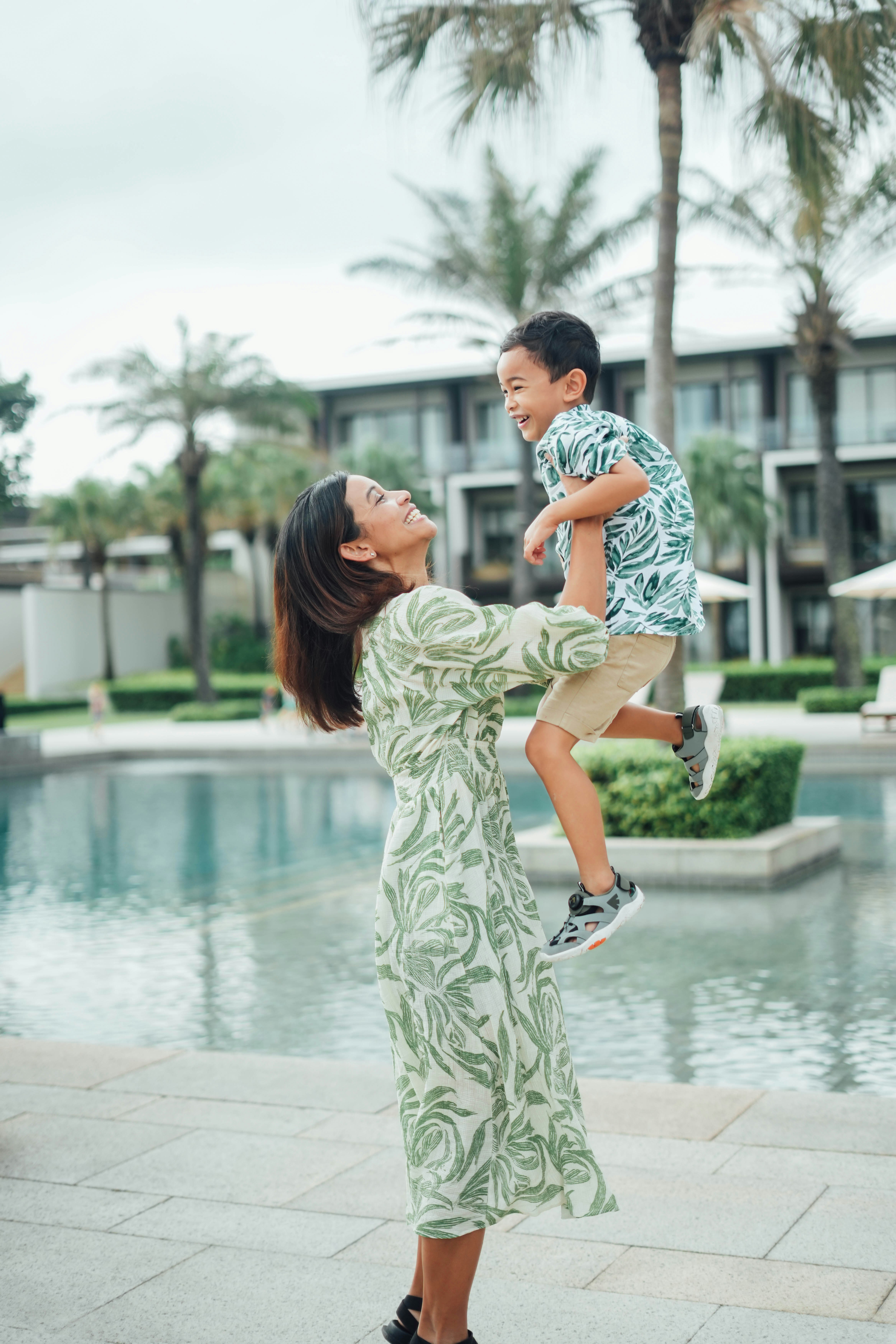 Mother lifts happy son by a pool