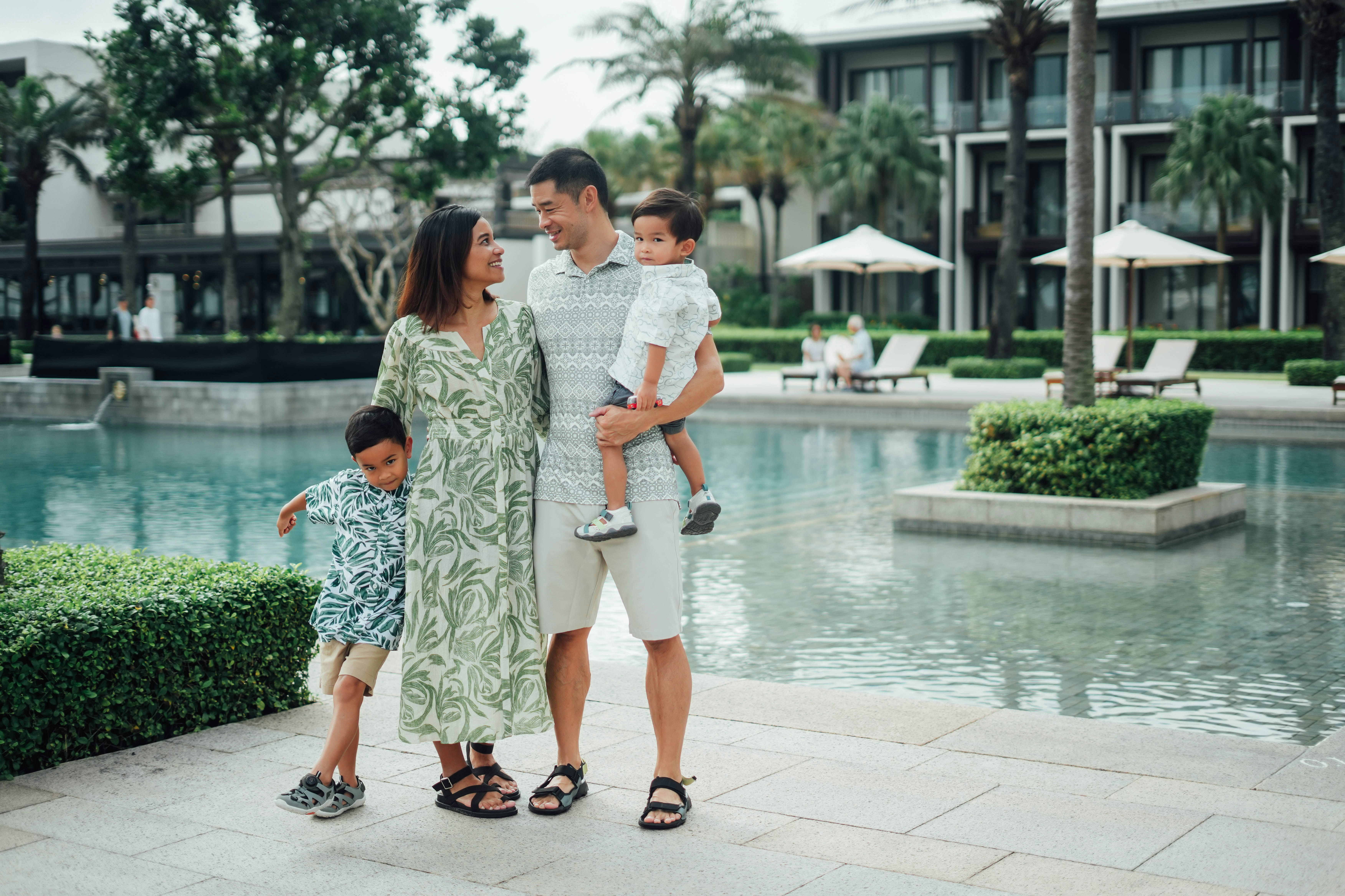 Family posing by the resort pool on a sunny day