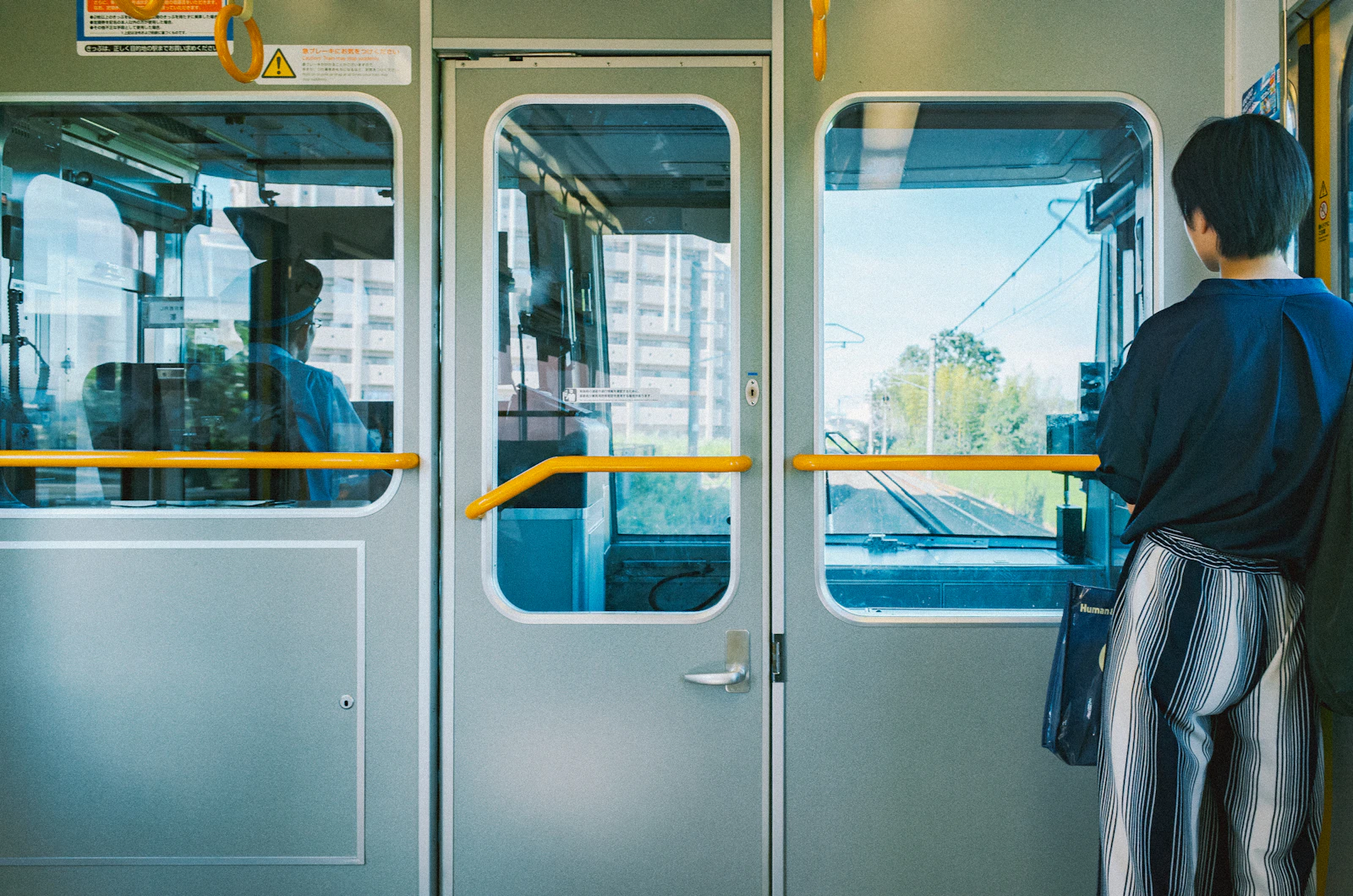 A seated passenger looks through a broad train window towards a dense city skyline.