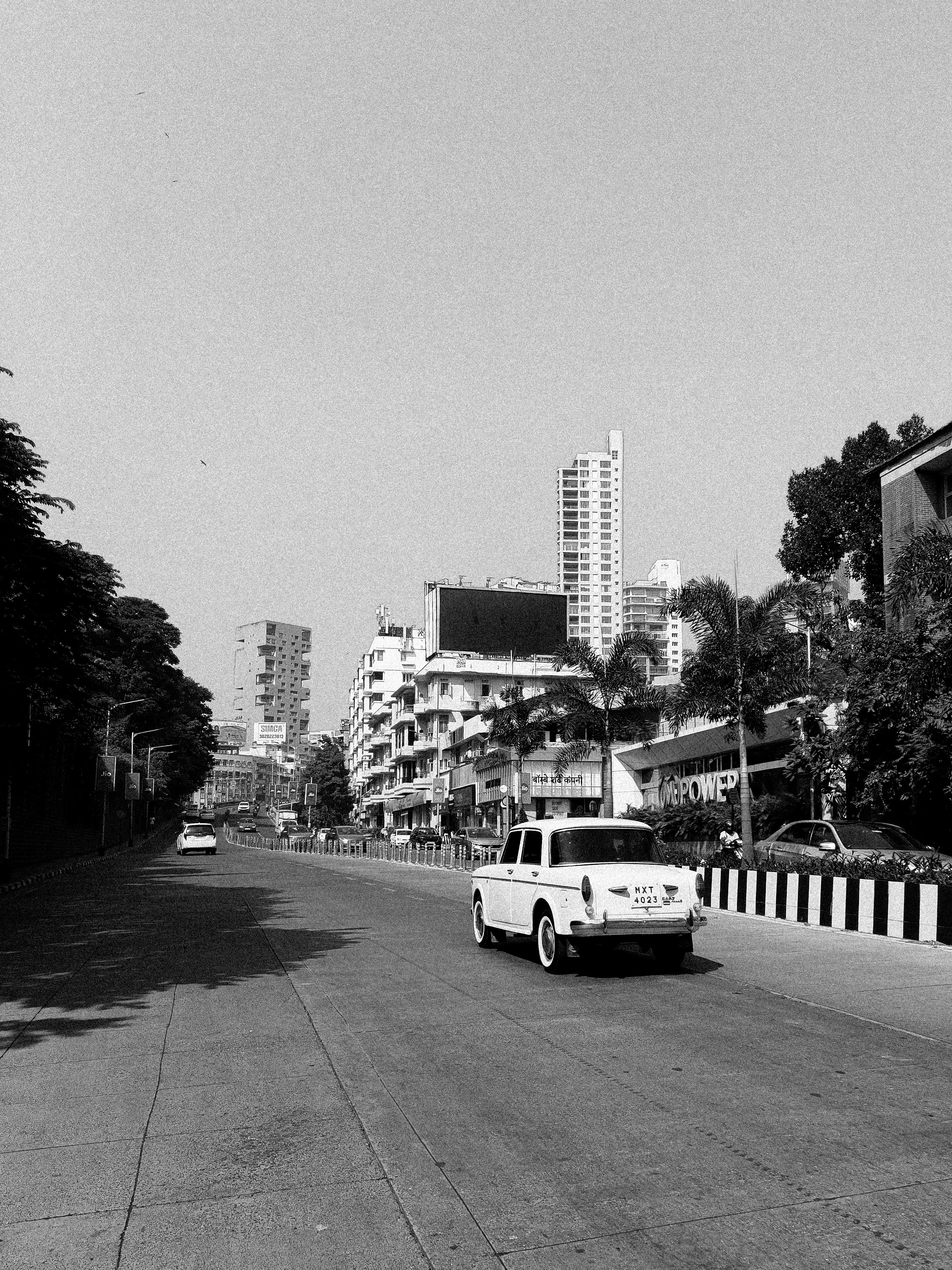 白い車が市街地の道路を走っている。