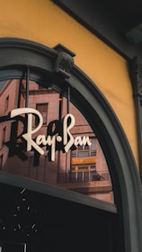 Ray-ban logo on a storefront with building reflections
