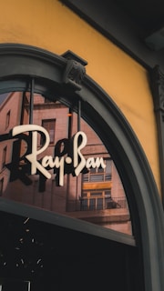 Ray-ban logo on a storefront with building reflections