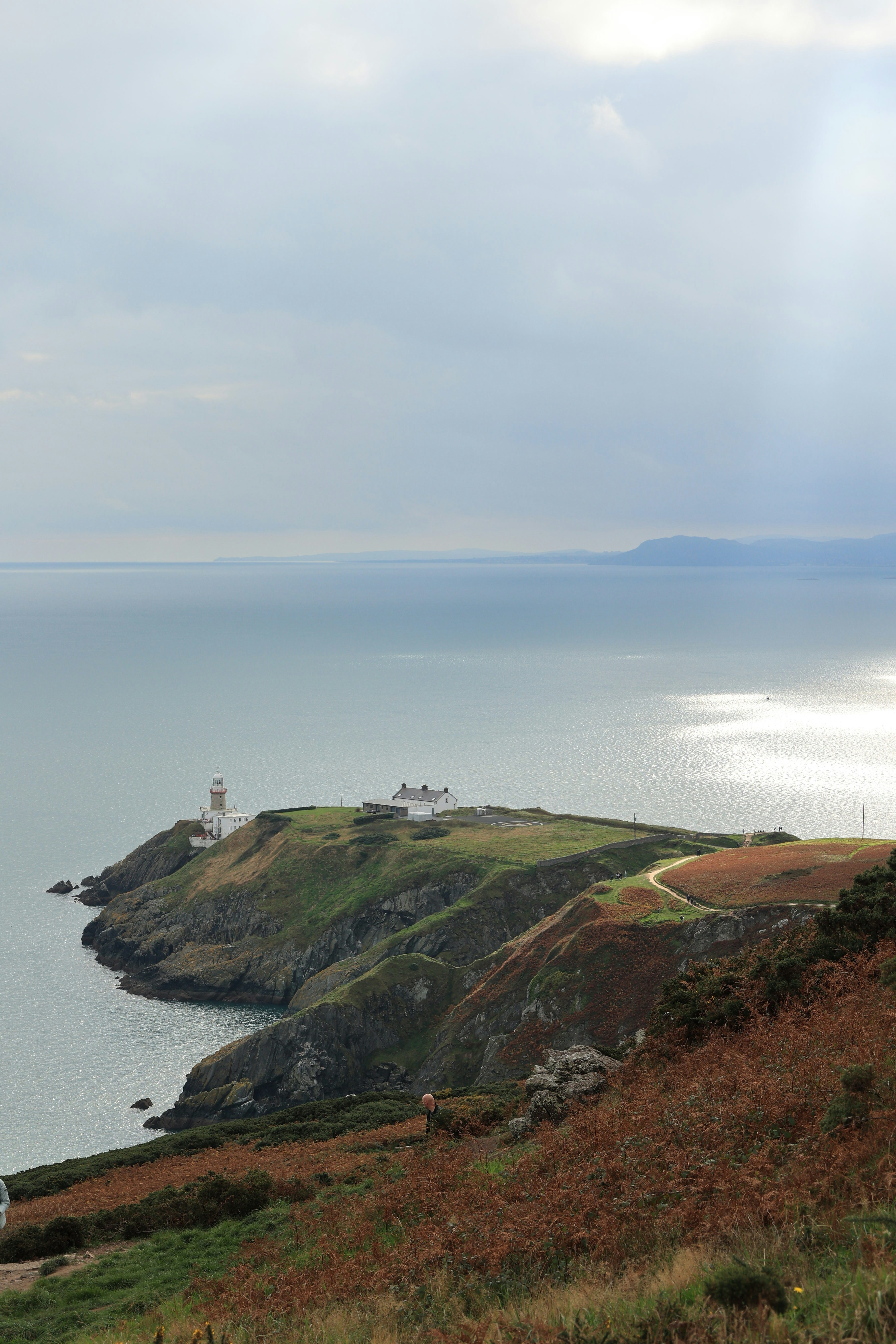 Lighthouse on a green cliff overlooking the ocean
