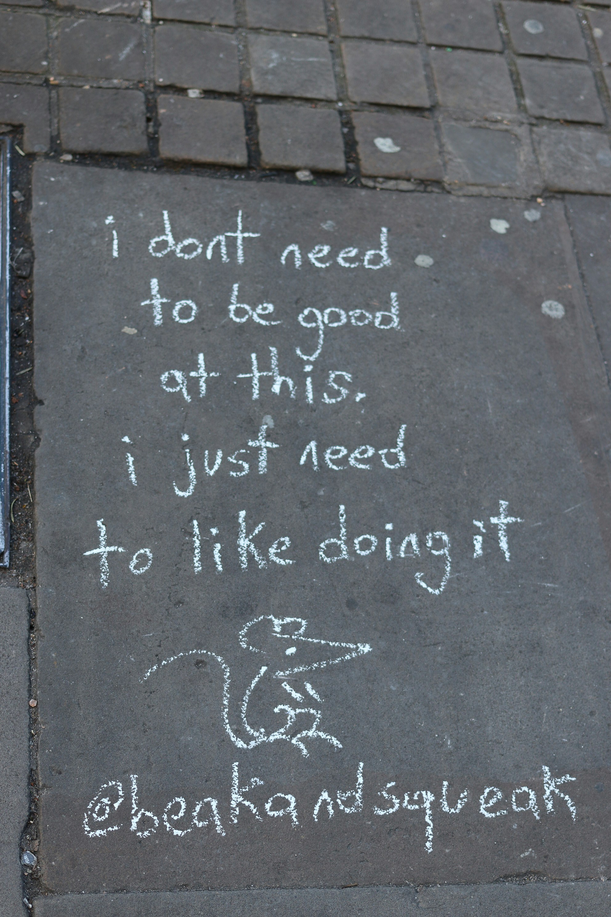 Chalk art on pavement with inspirational quote and drawing