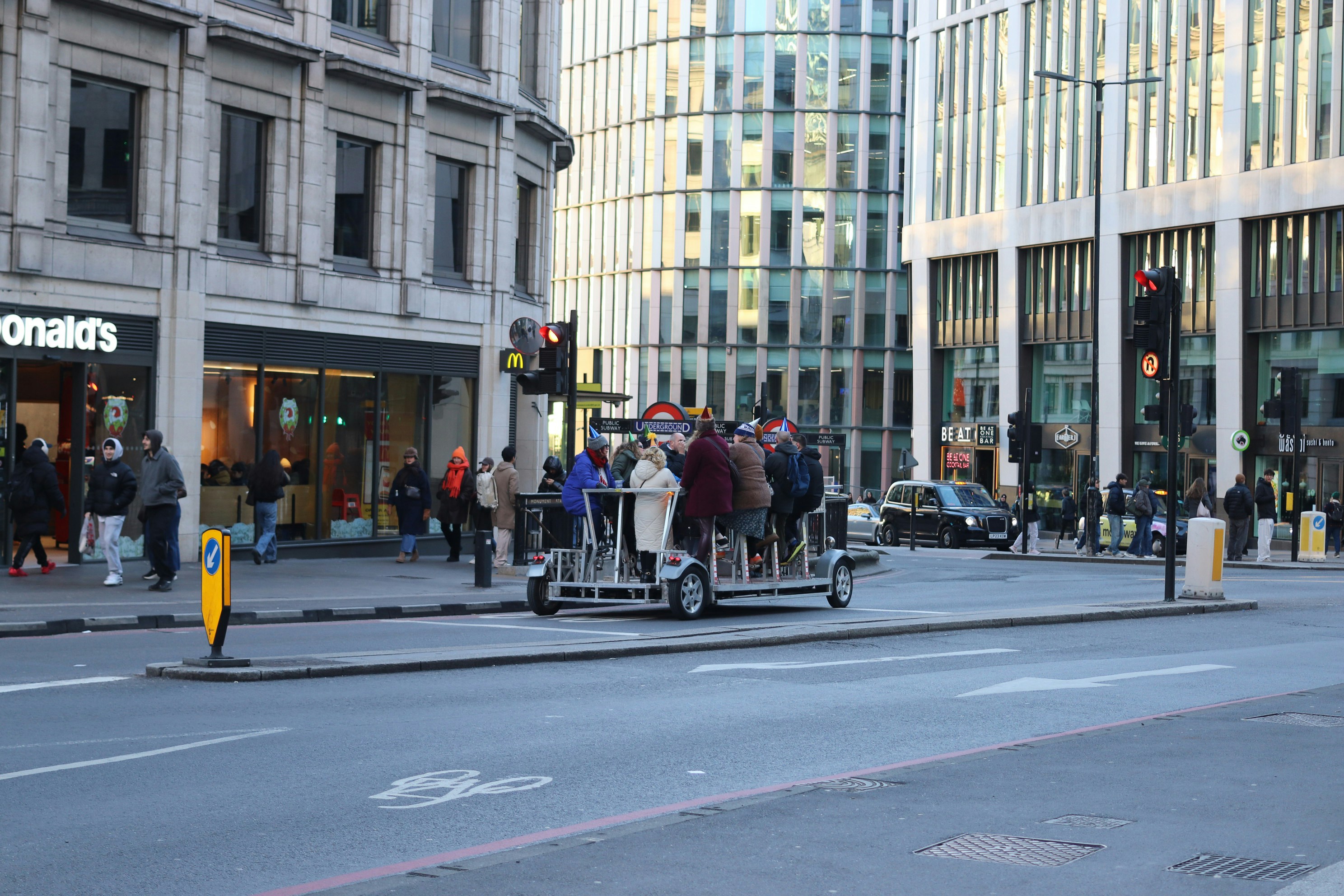 People riding a pedal-powered bus on a city street