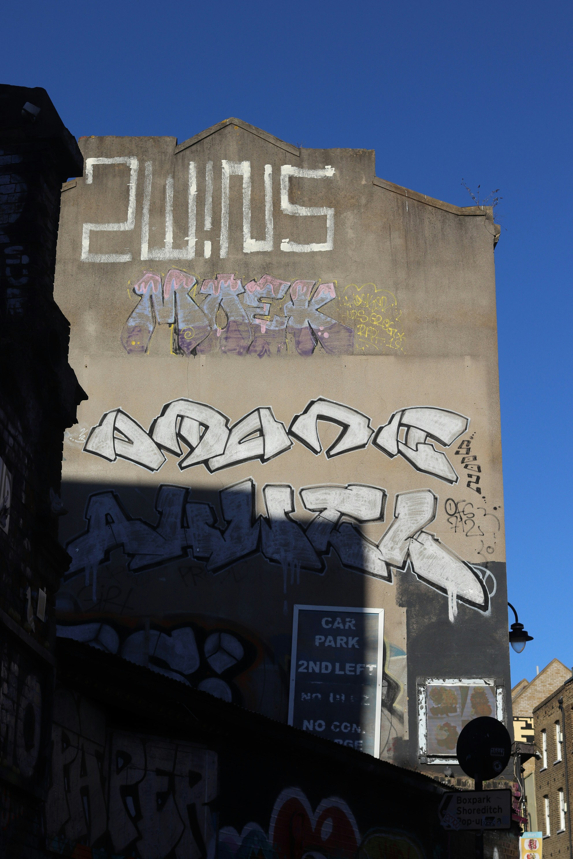Graffiti art covers a building wall under blue sky