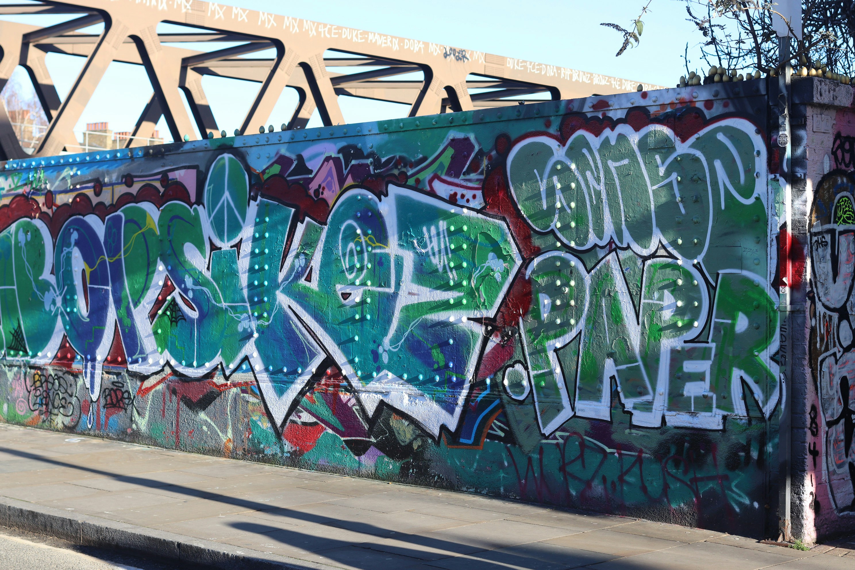 Colorful graffiti art covers a concrete wall under a bridge