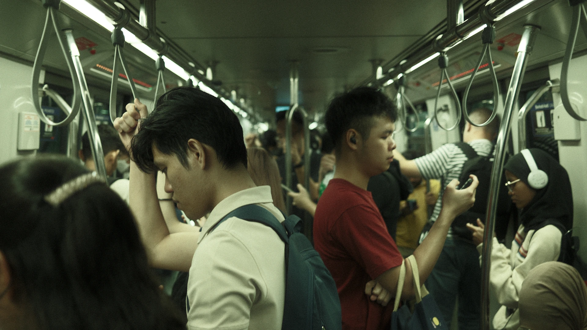 Crowded subway car with passengers holding onto poles.