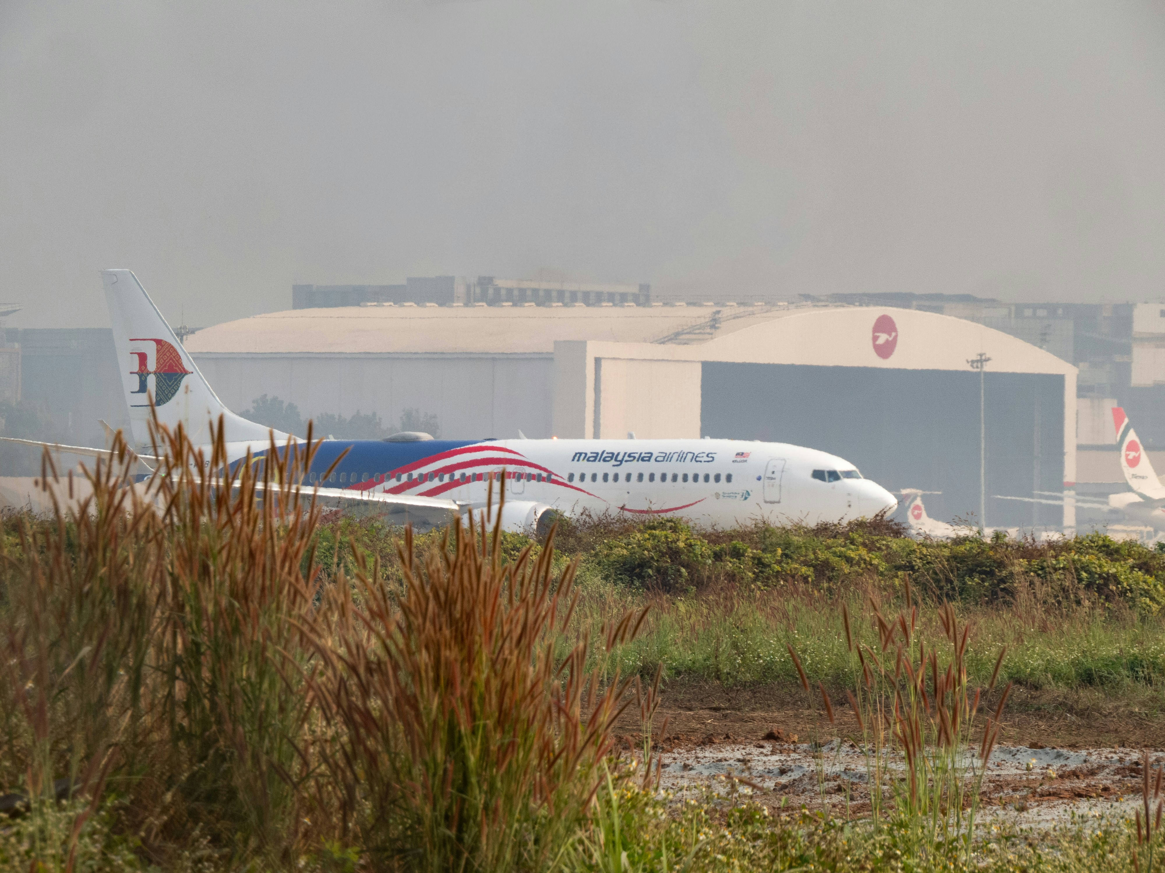 Malaysian airlines airplane on tarmac near hangar