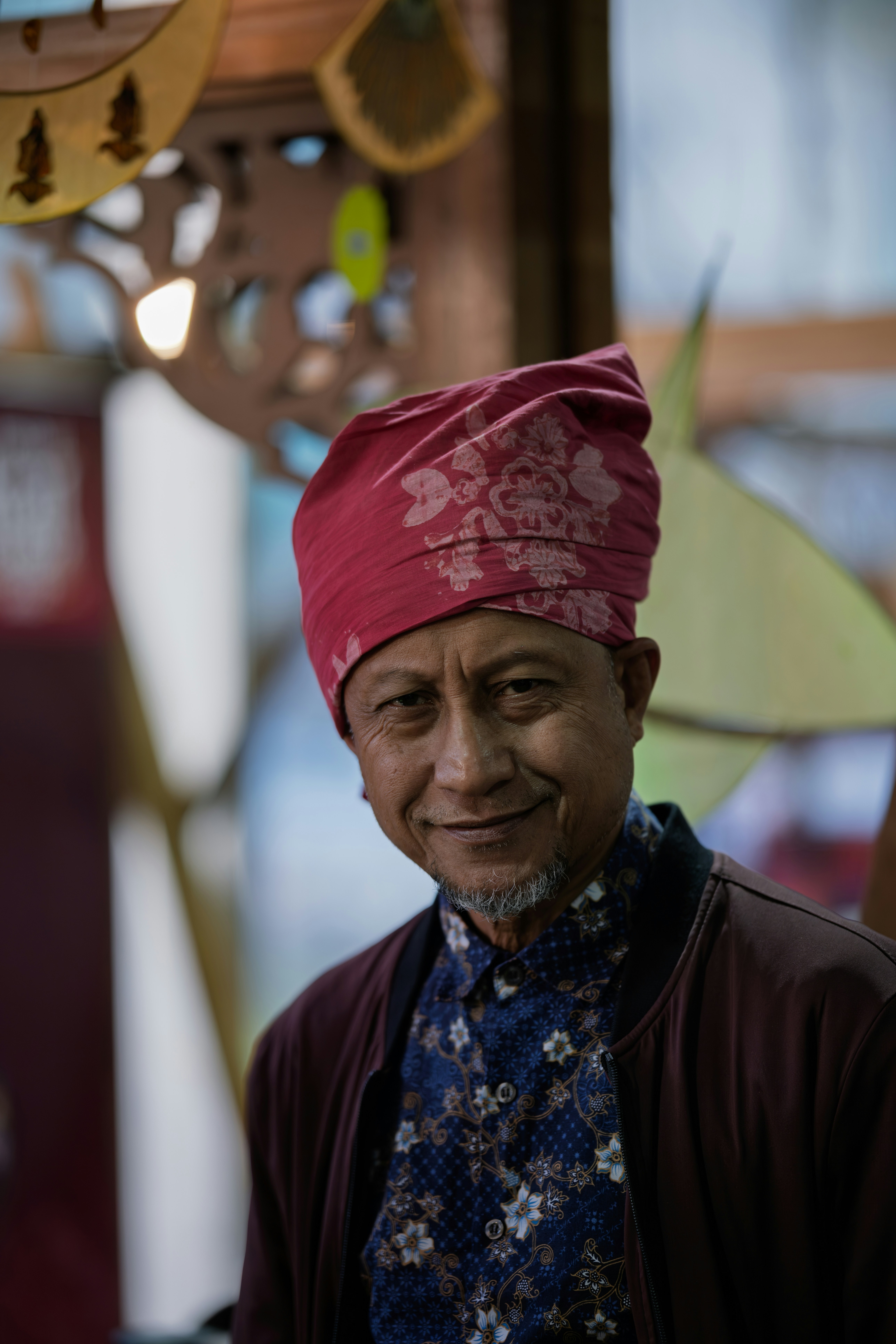 Man wearing a red headscarf and patterned shirt.