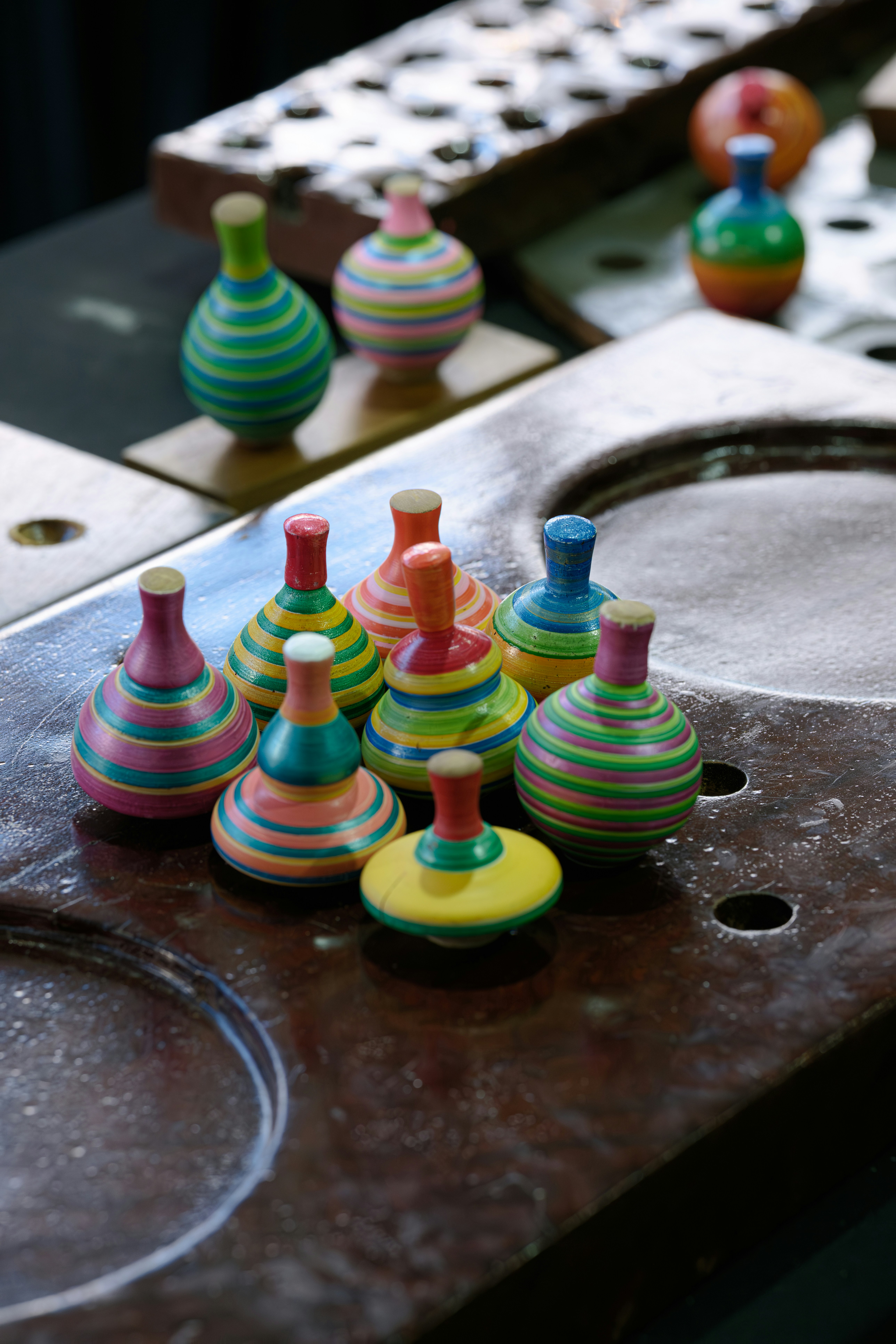 Colorful wooden spinning tops arranged on a surface.