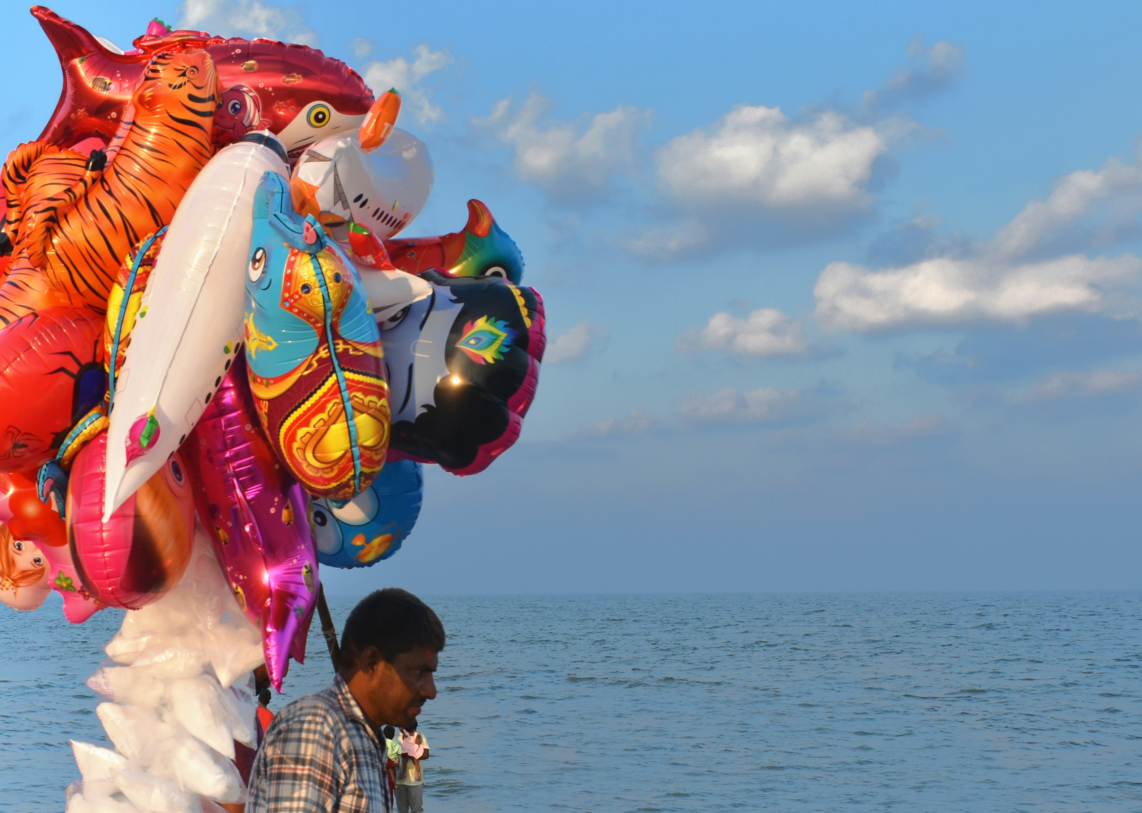Man holding colorful balloons by the ocean