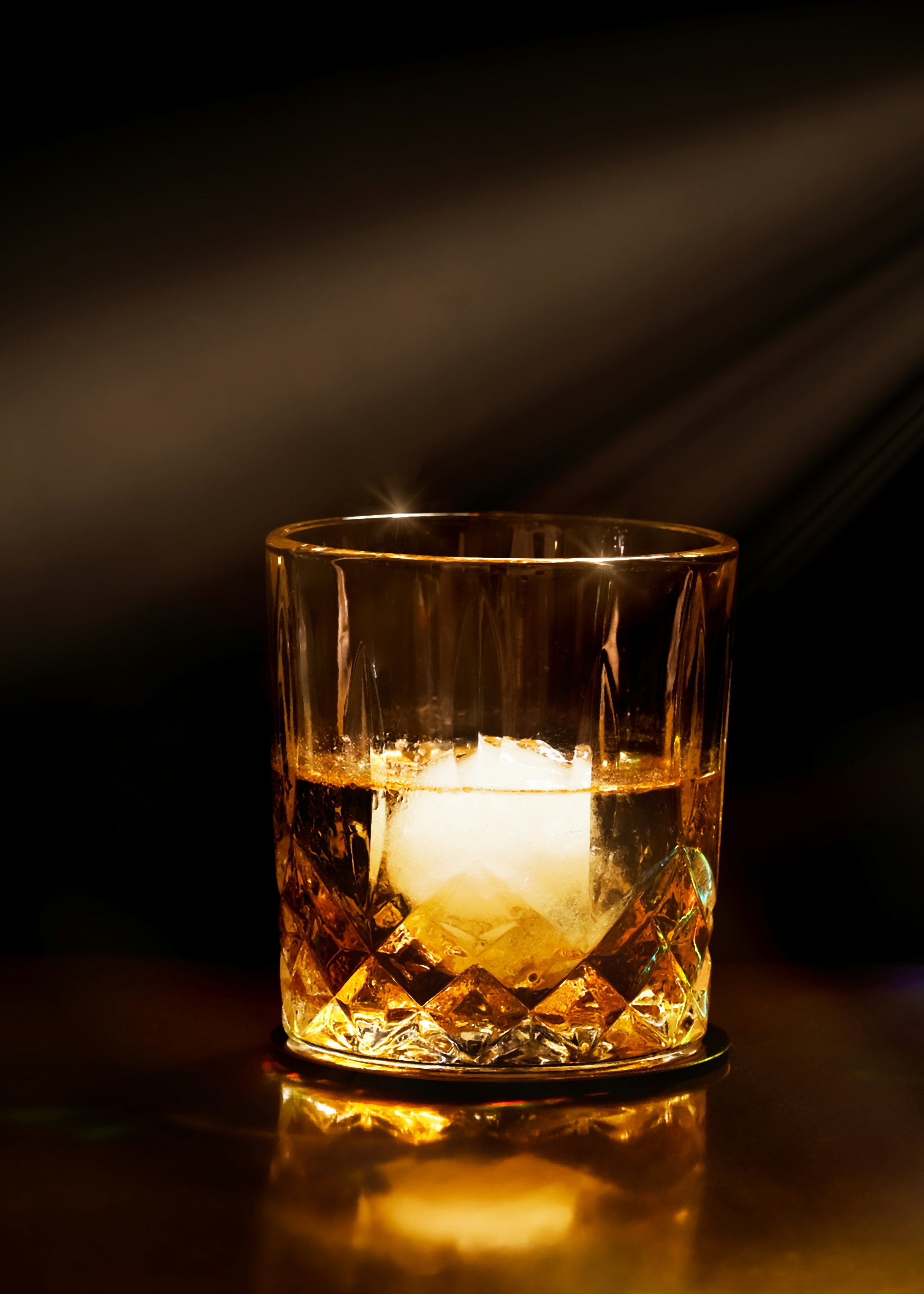A glass of whiskey with a large ice sphere.
