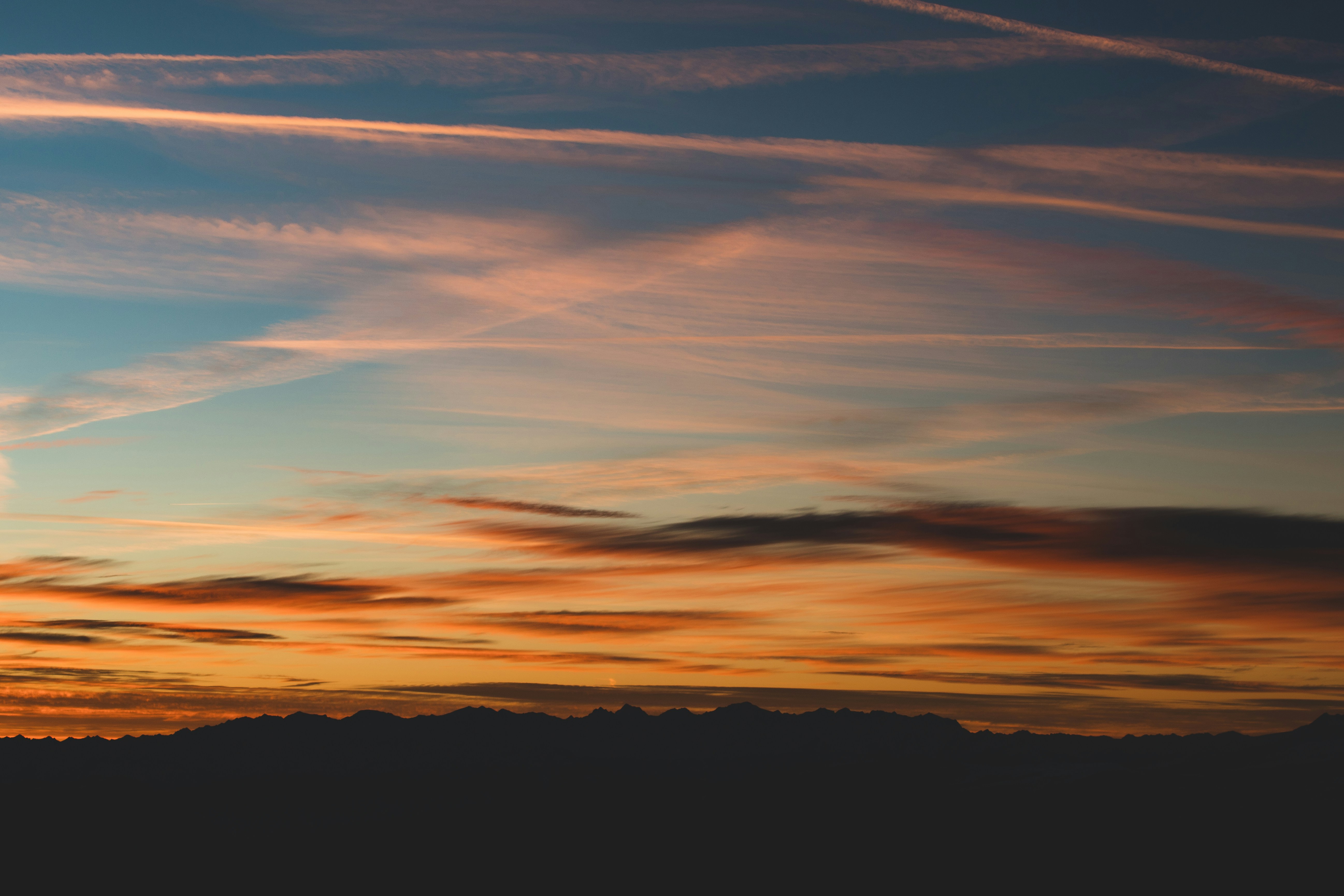 Sunset sky with wispy clouds over dark horizon