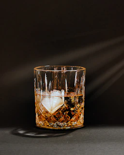 A glass of whiskey with a large ice cube