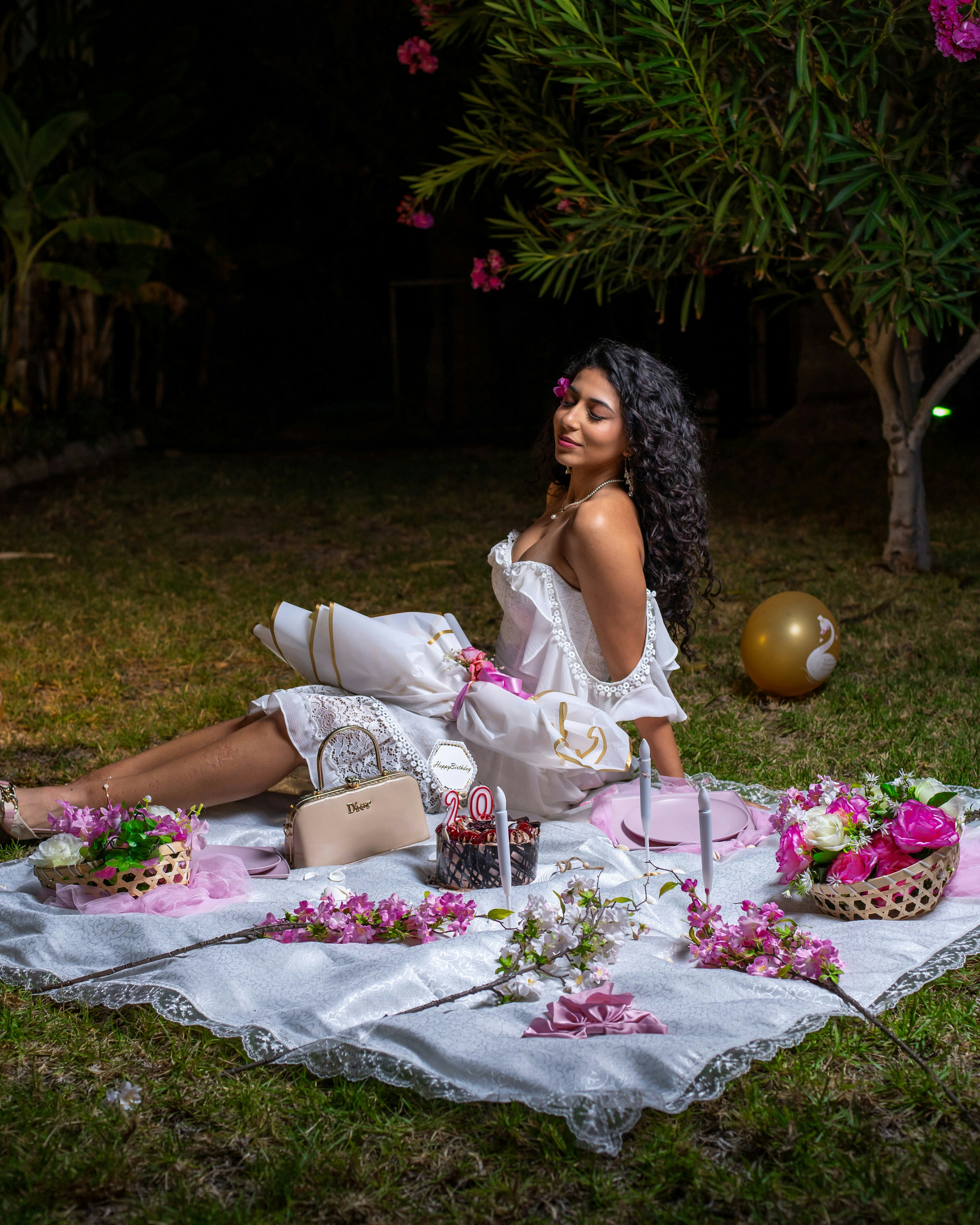 Woman relaxing at a nighttime picnic with flowers