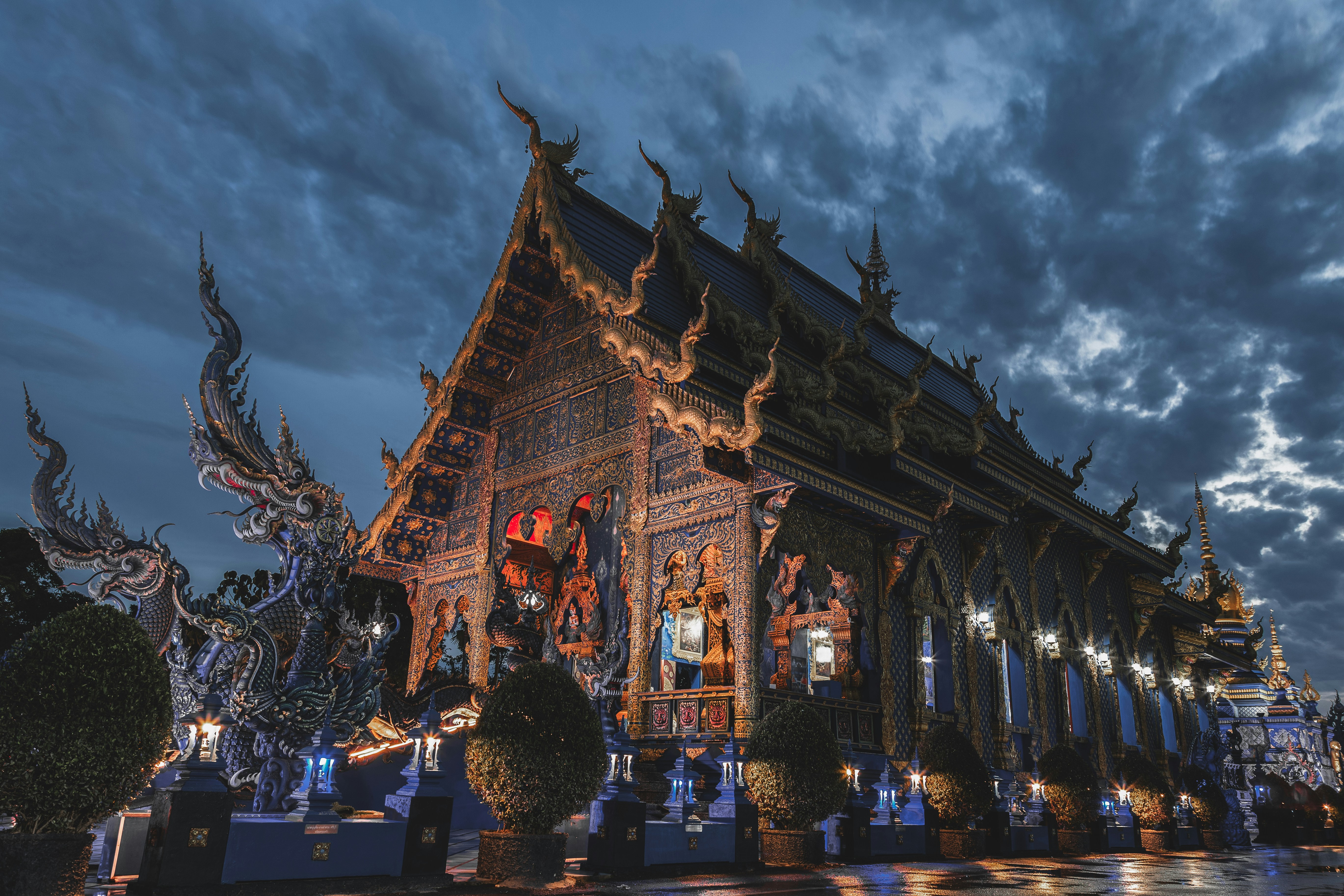 Ornate temple building illuminated at night under cloudy sky